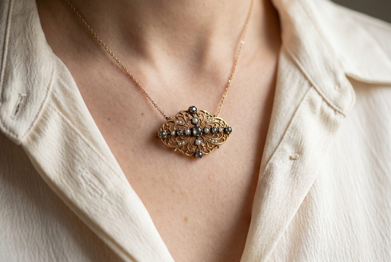 An antique brooch worn as a pendant on a fine gold chain