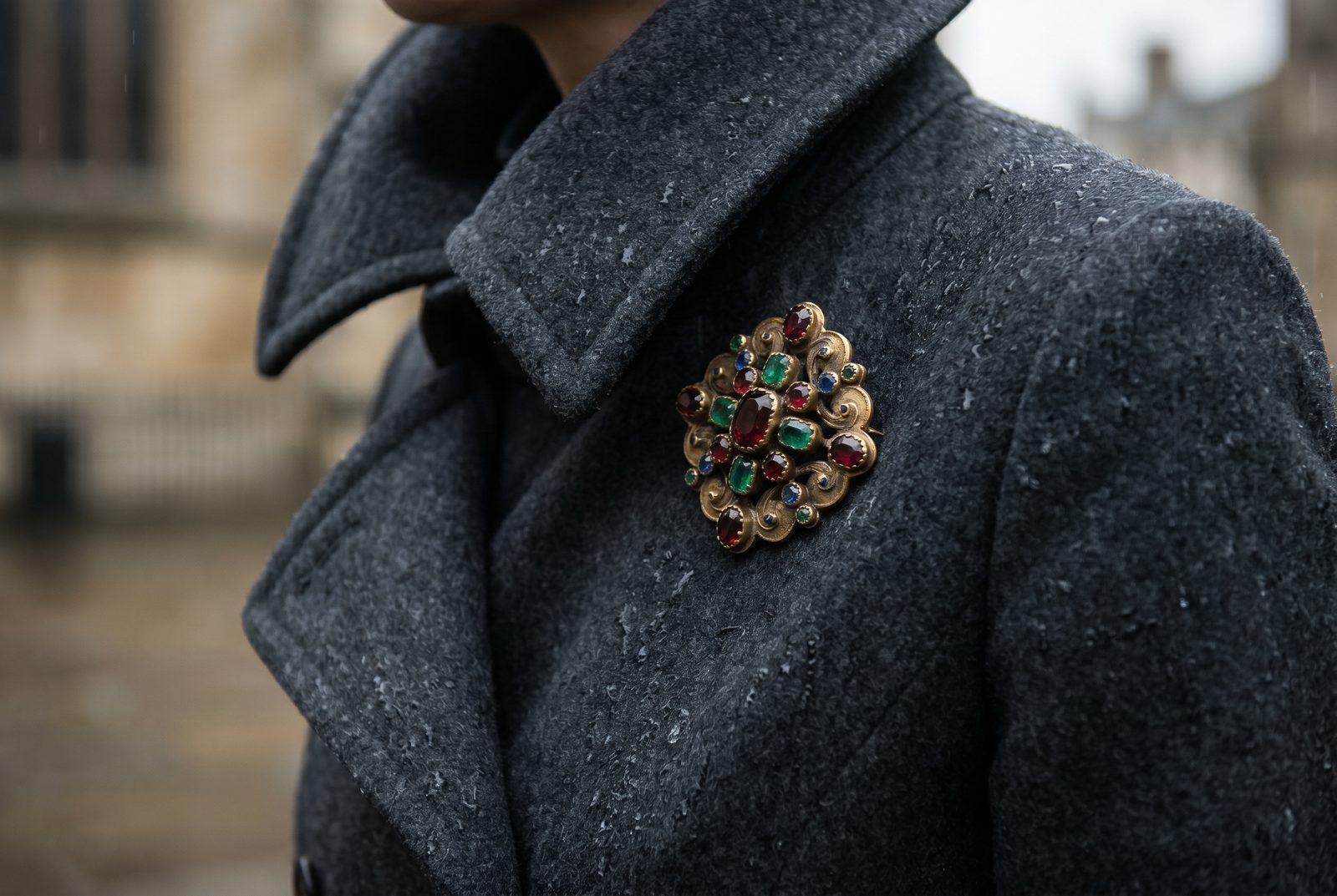 An antique gold and gemstone brooch styled on a wool winter coat collar