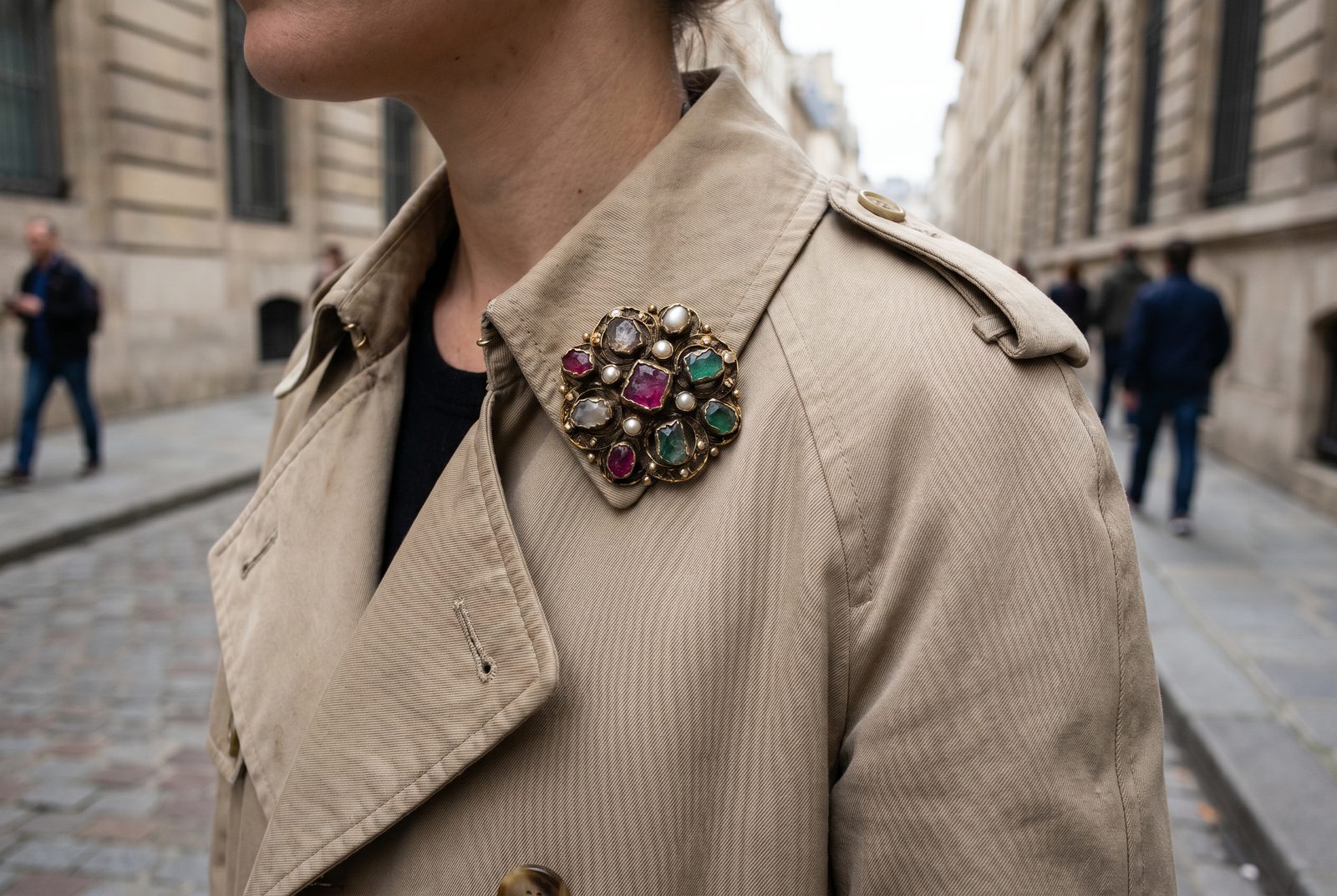 An antique brooch styled on a trench coat lapel for everyday street style