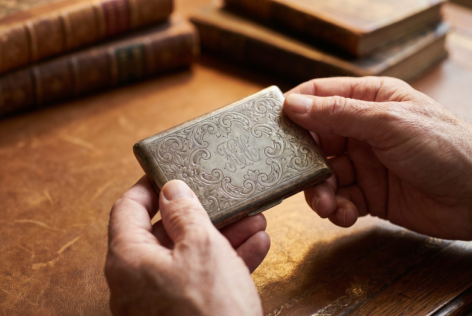 An antique engraved sterling silver calling card case held in the hand