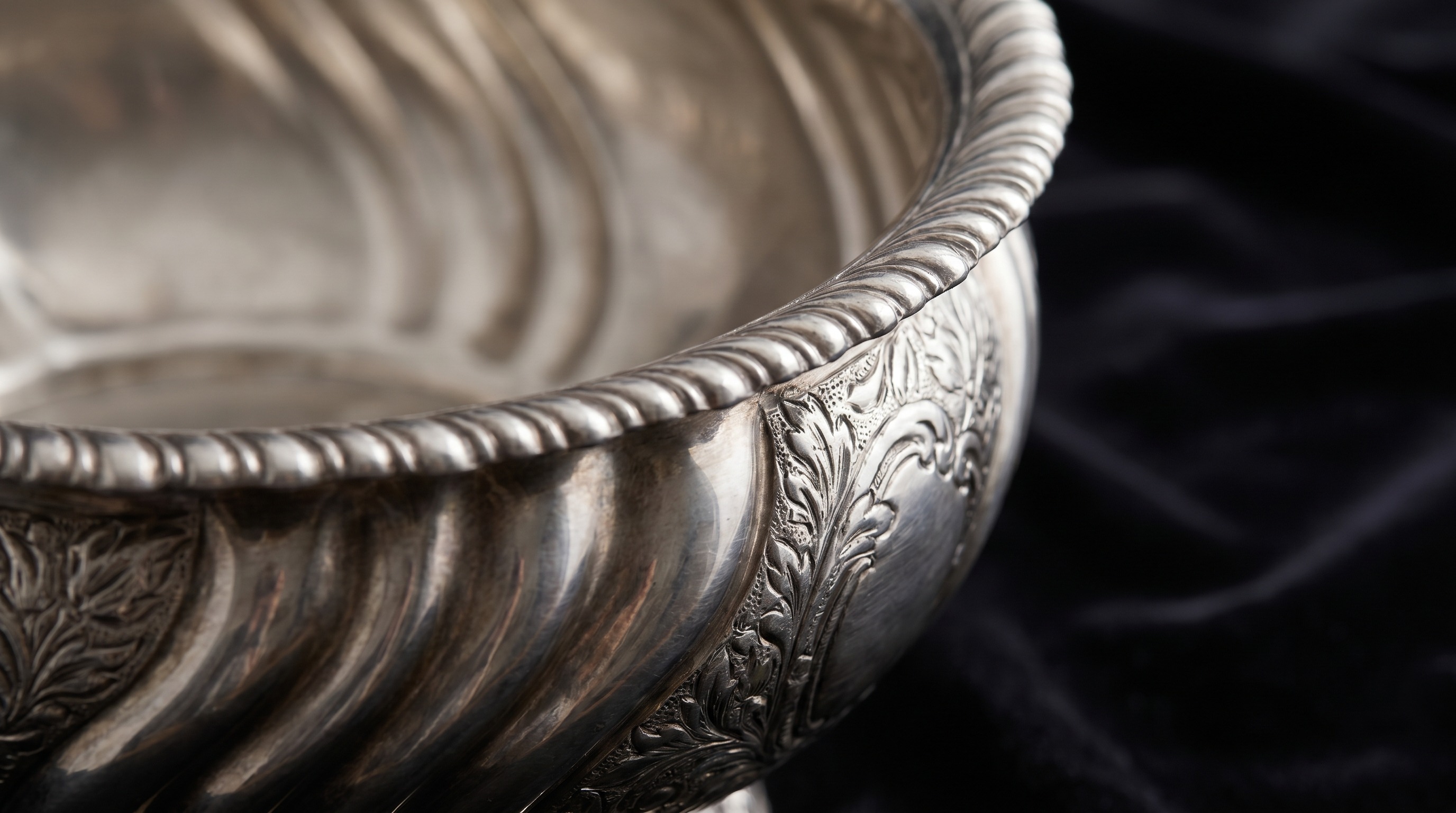 Gadrooned rim and chased body of an antique silver punch bowl