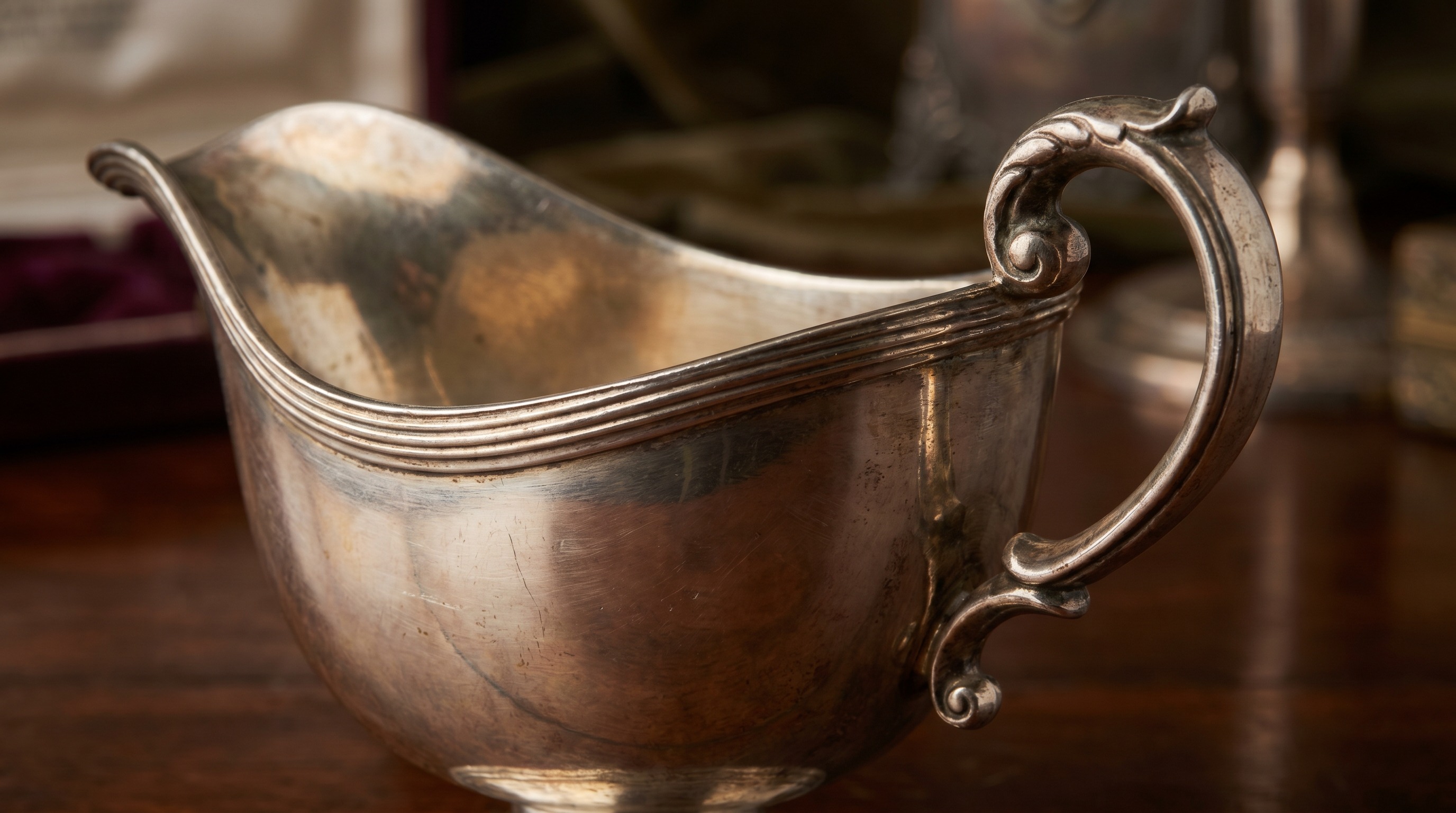 Spout, shaped rim and scroll handle of an antique silver sauce boat
