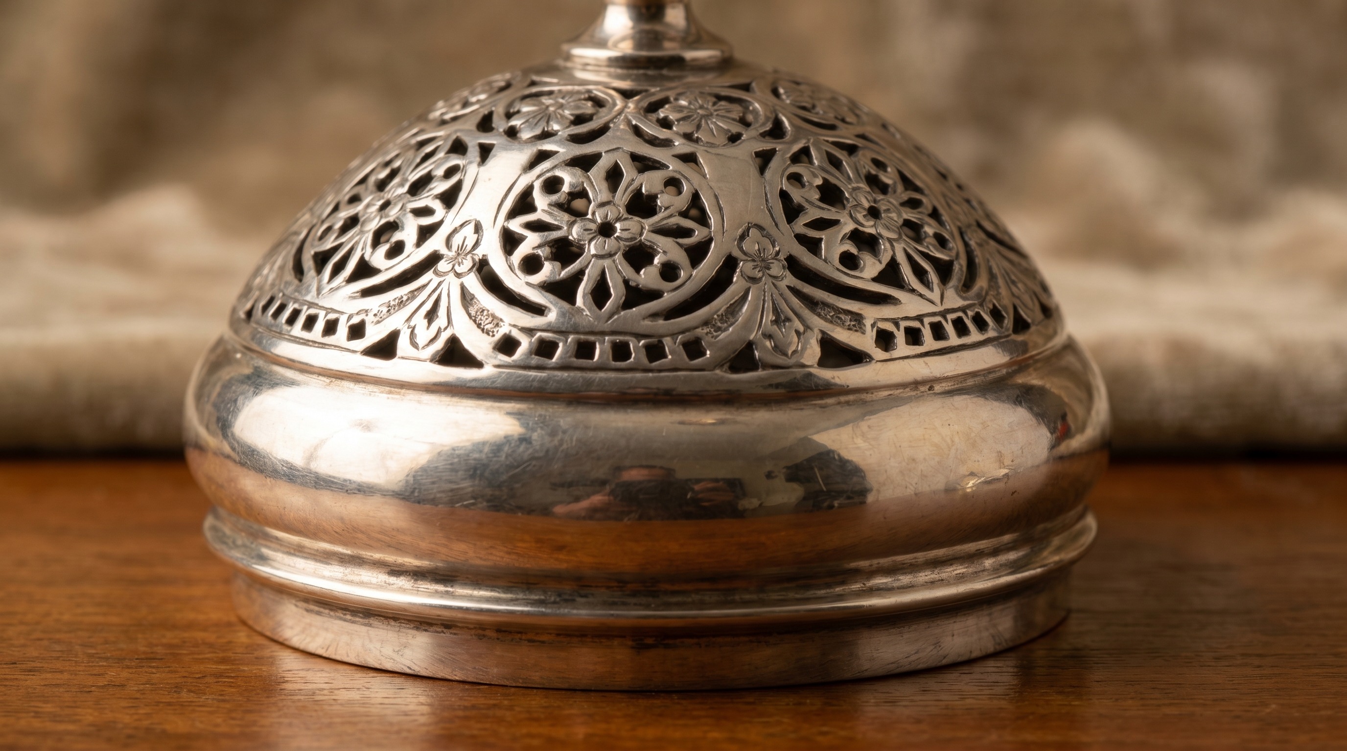 Close-up of the pierced domed lid of an antique silver sugar caster
