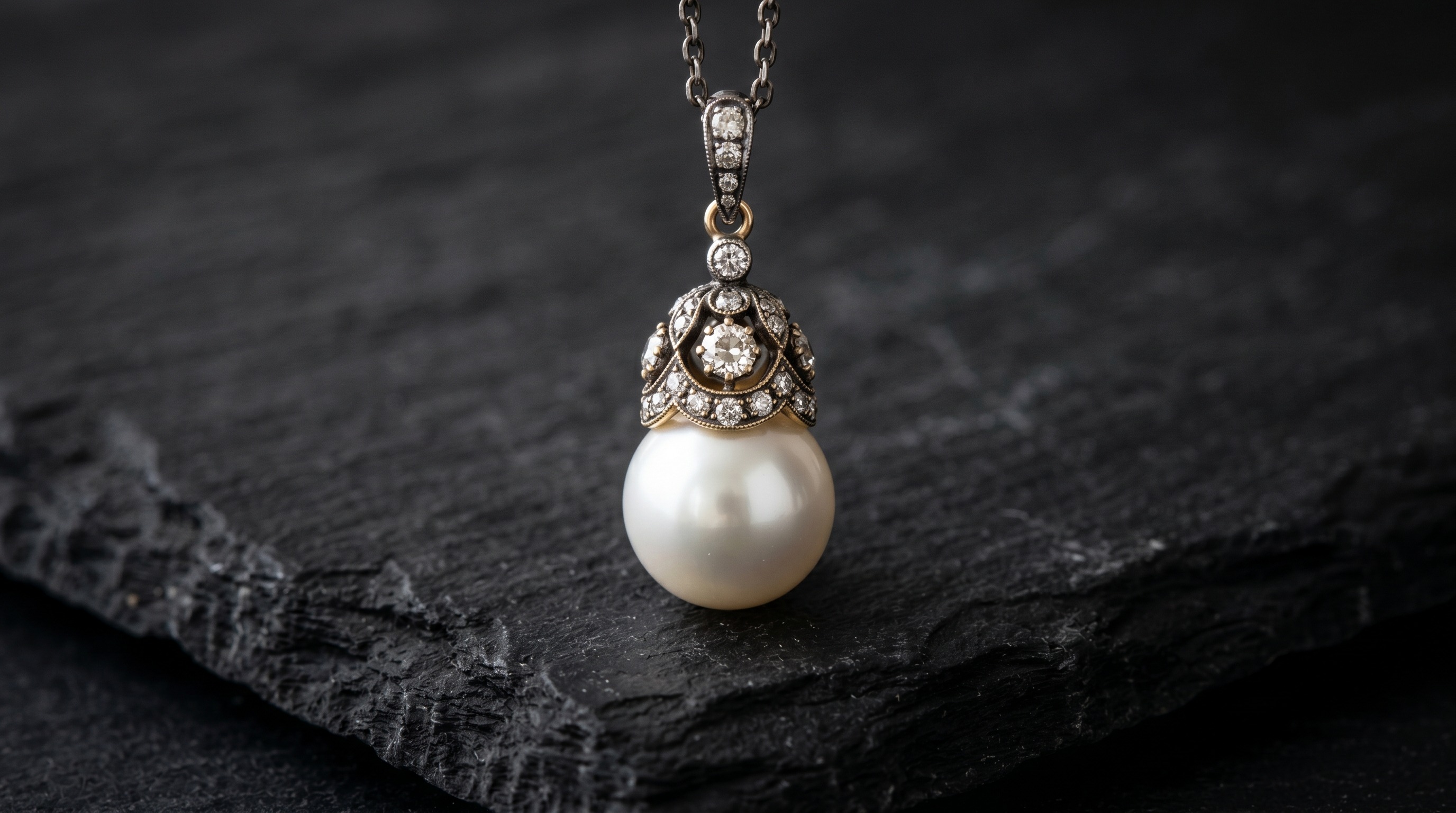 Antique pearl and diamond pendant, the June birthstone, on a dark editorial background