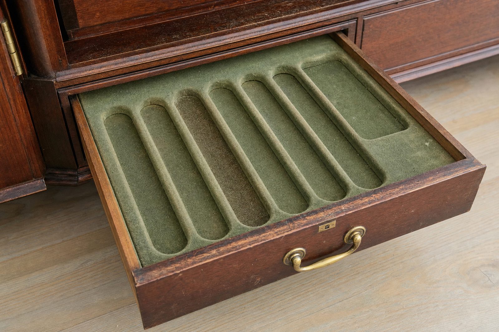 Open drawer of an antique mahogany canteen showing empty fitted green baize compartments