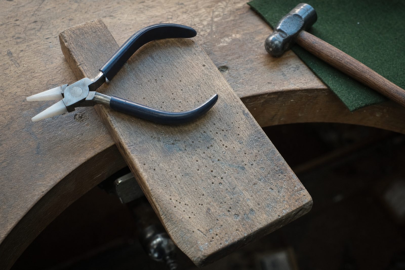 Jeweller's bench pin with ring-shaping pliers, planishing hammer and green baize