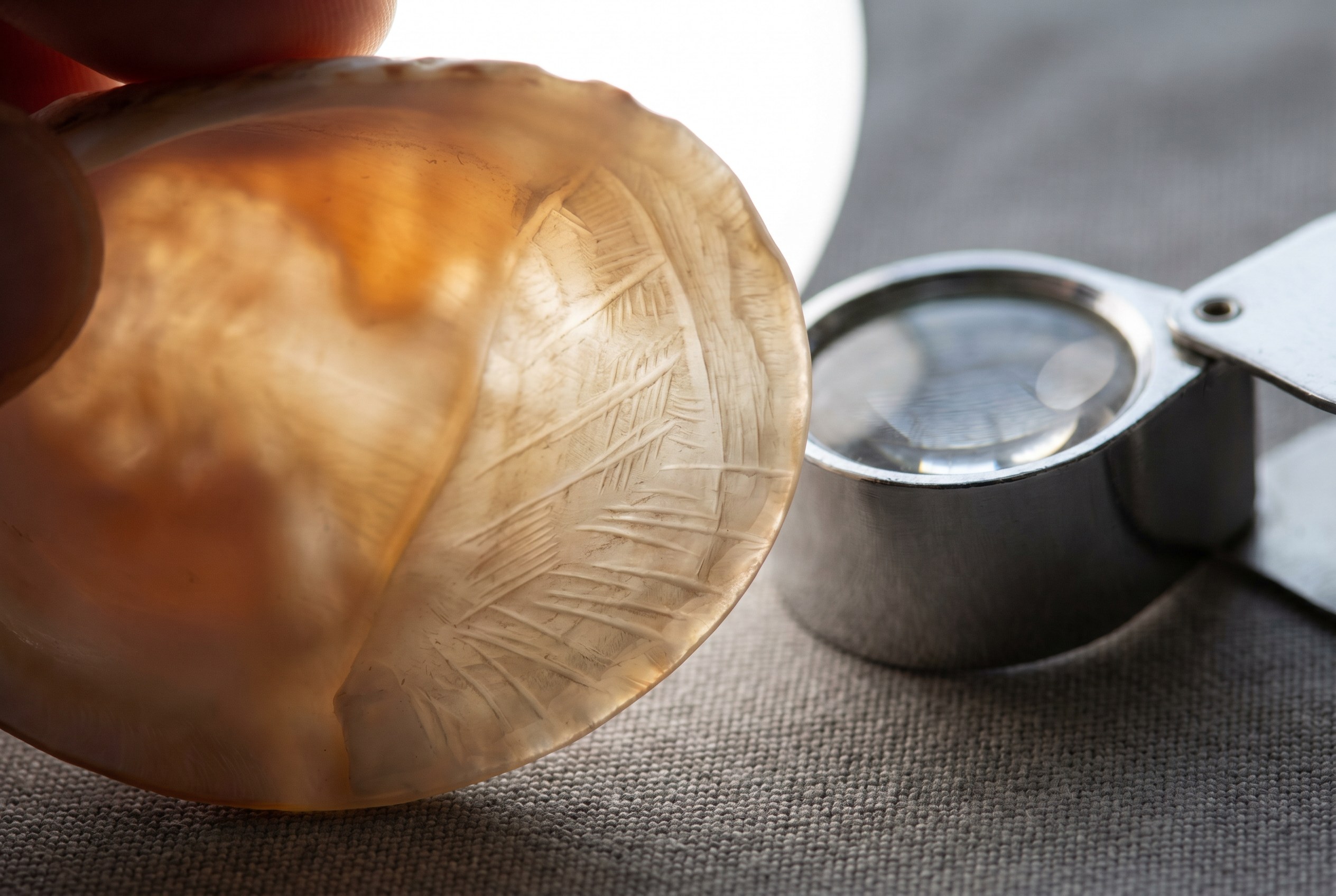 Carved edge detail of a genuine shell cameo with jeweller loupe