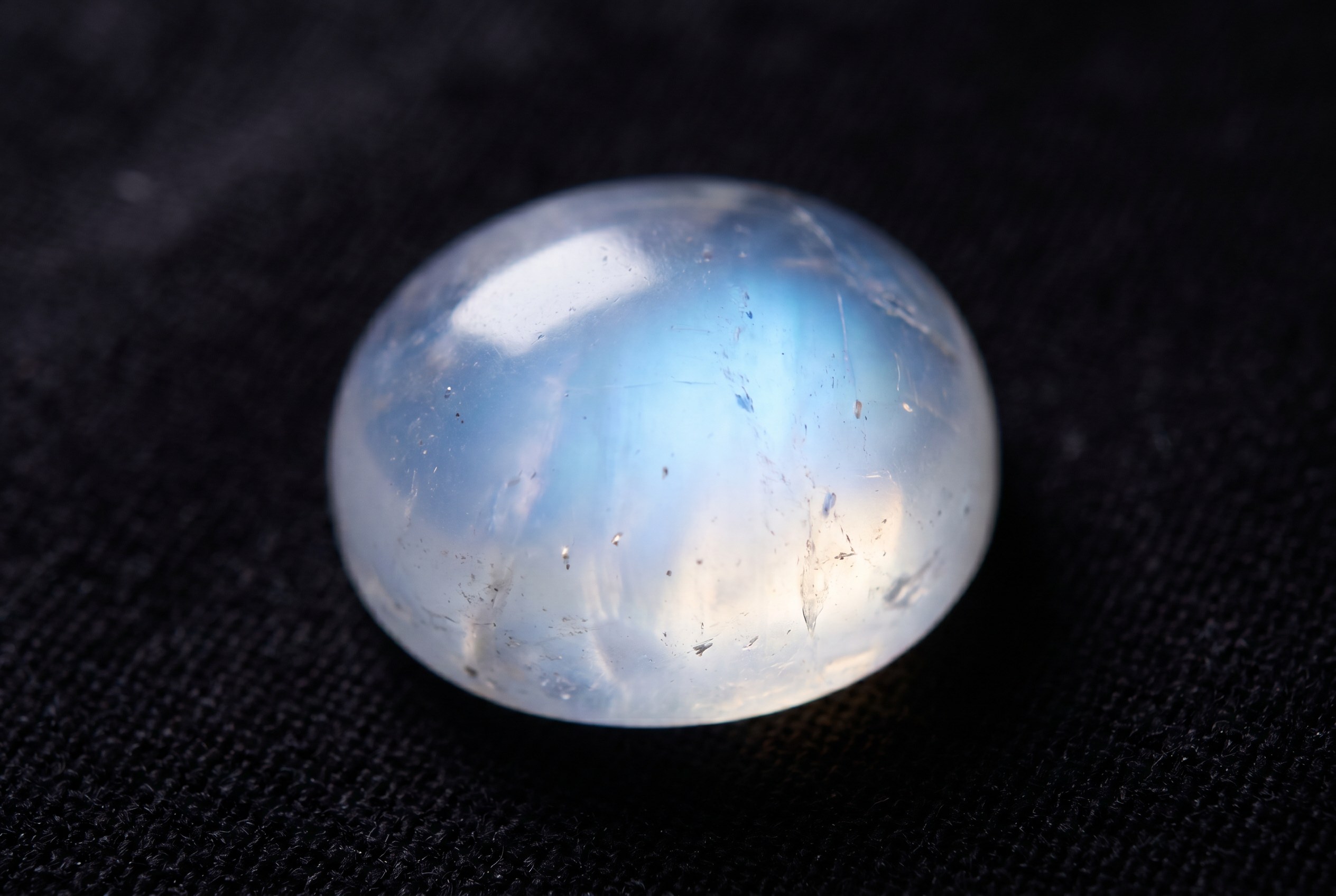 Cabochon moonstone glowing with blue adularescence