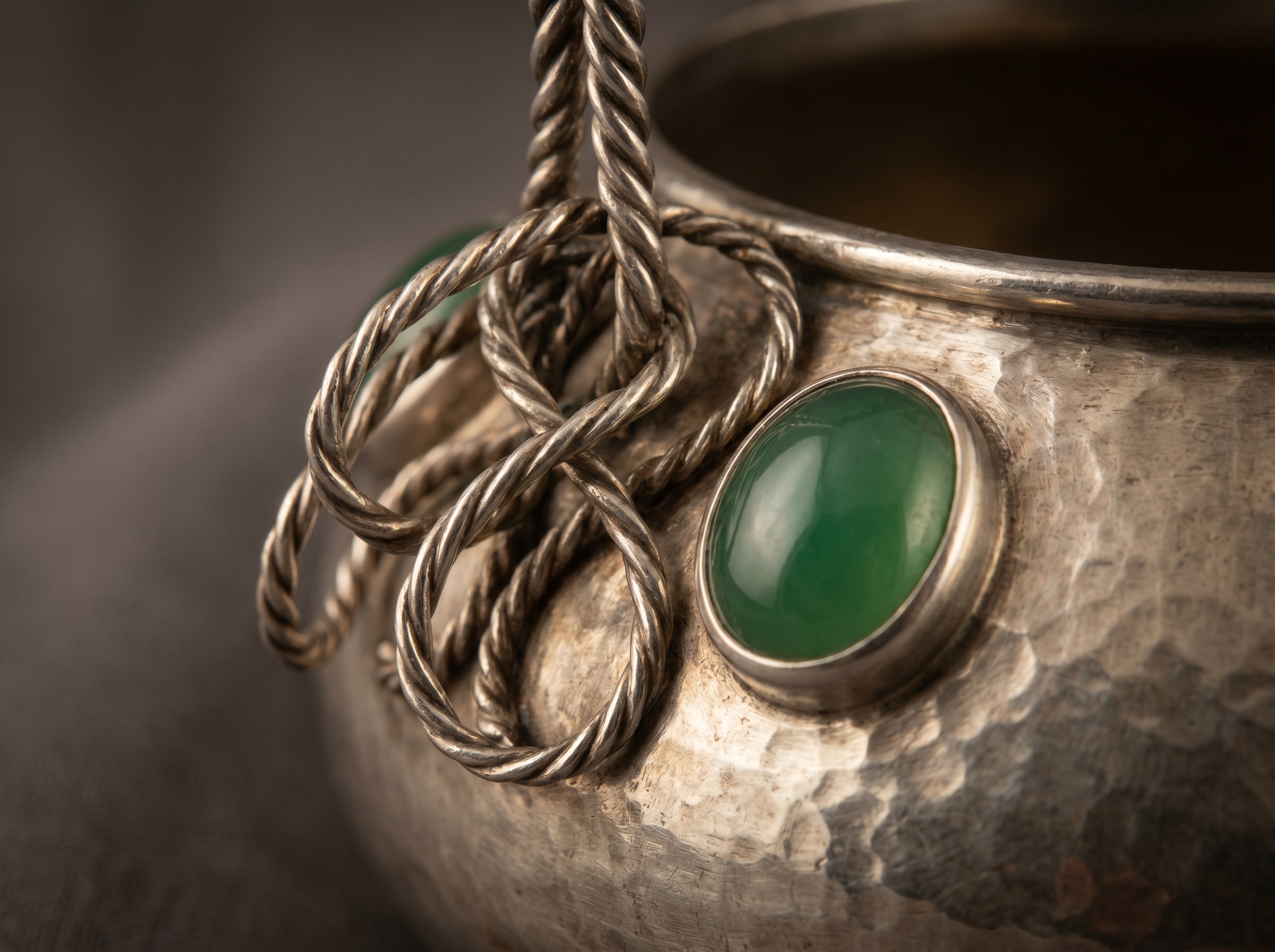 Looped silver wirework handle and green cabochon stone on Arts and Crafts silver in the C.R. Ashbee style — macro