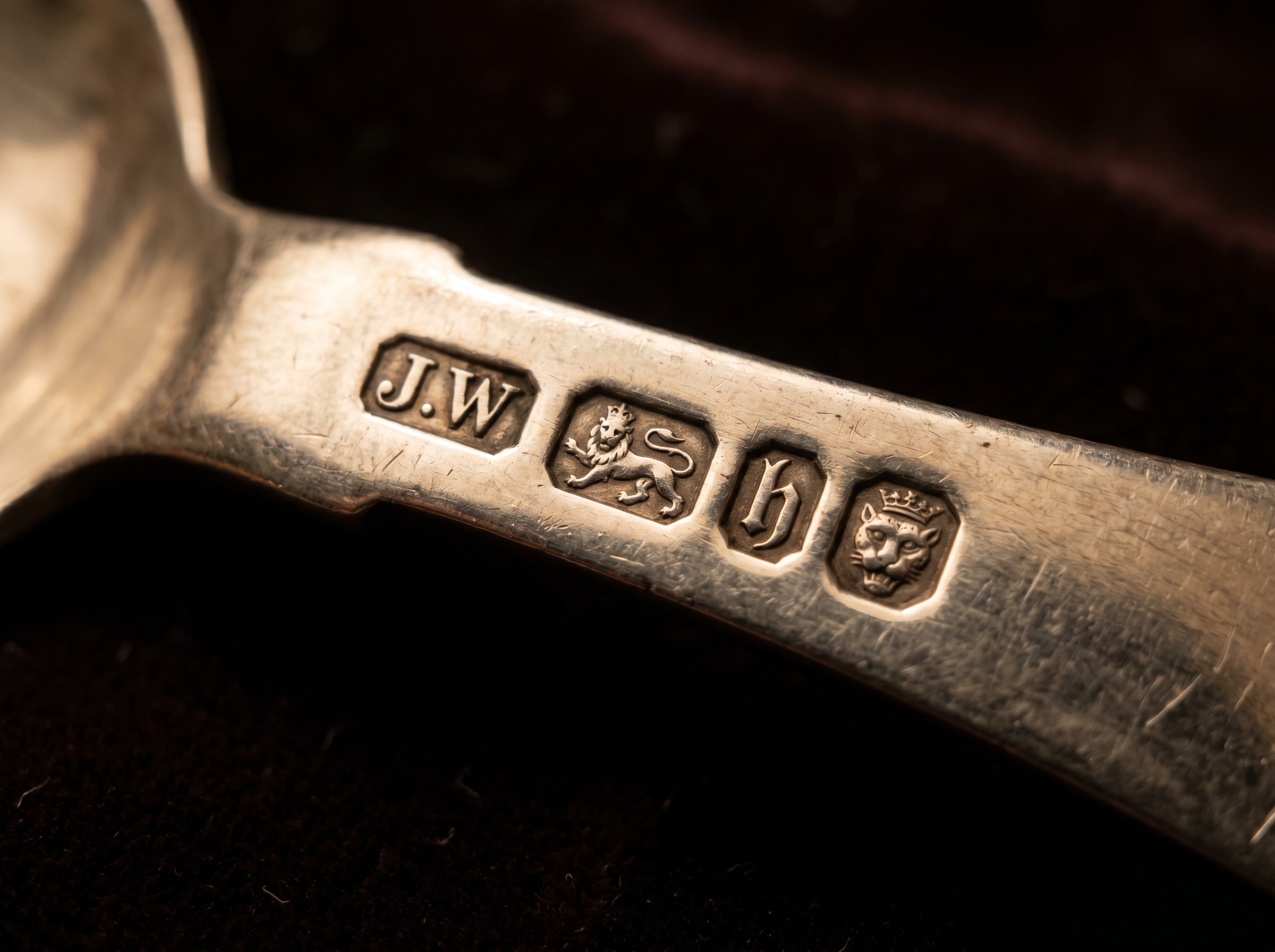 Extreme macro of London silver hallmarks — maker's mark, leopard's head, lion passant, date letter