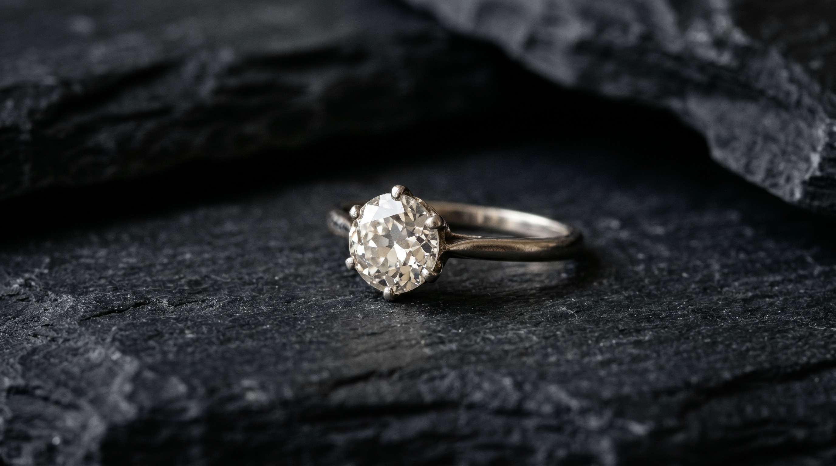 Antique diamond solitaire engagement ring on a dark editorial background
