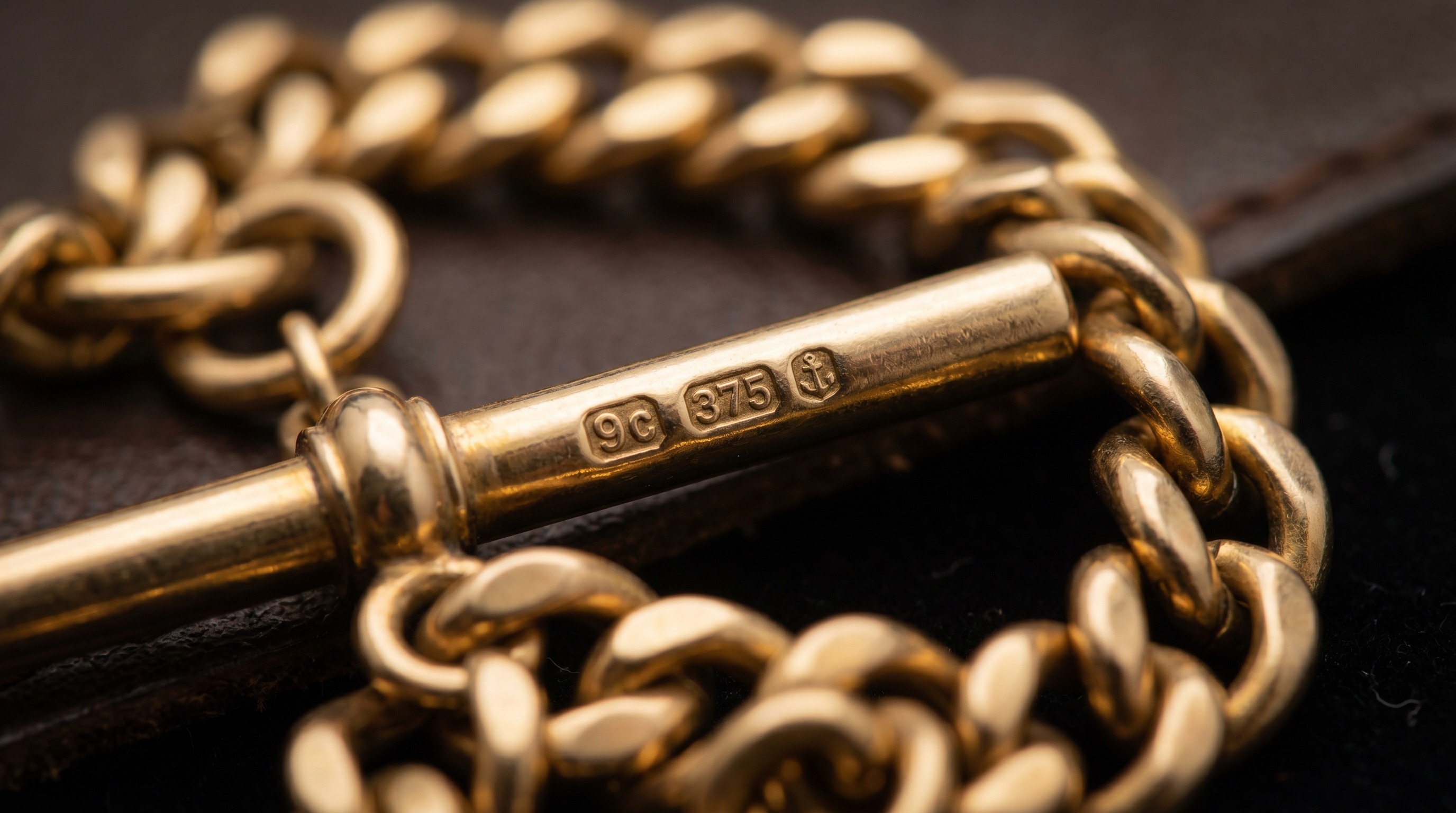 Macro of hallmark stamps on the T-bar and links of a gold Albert chain