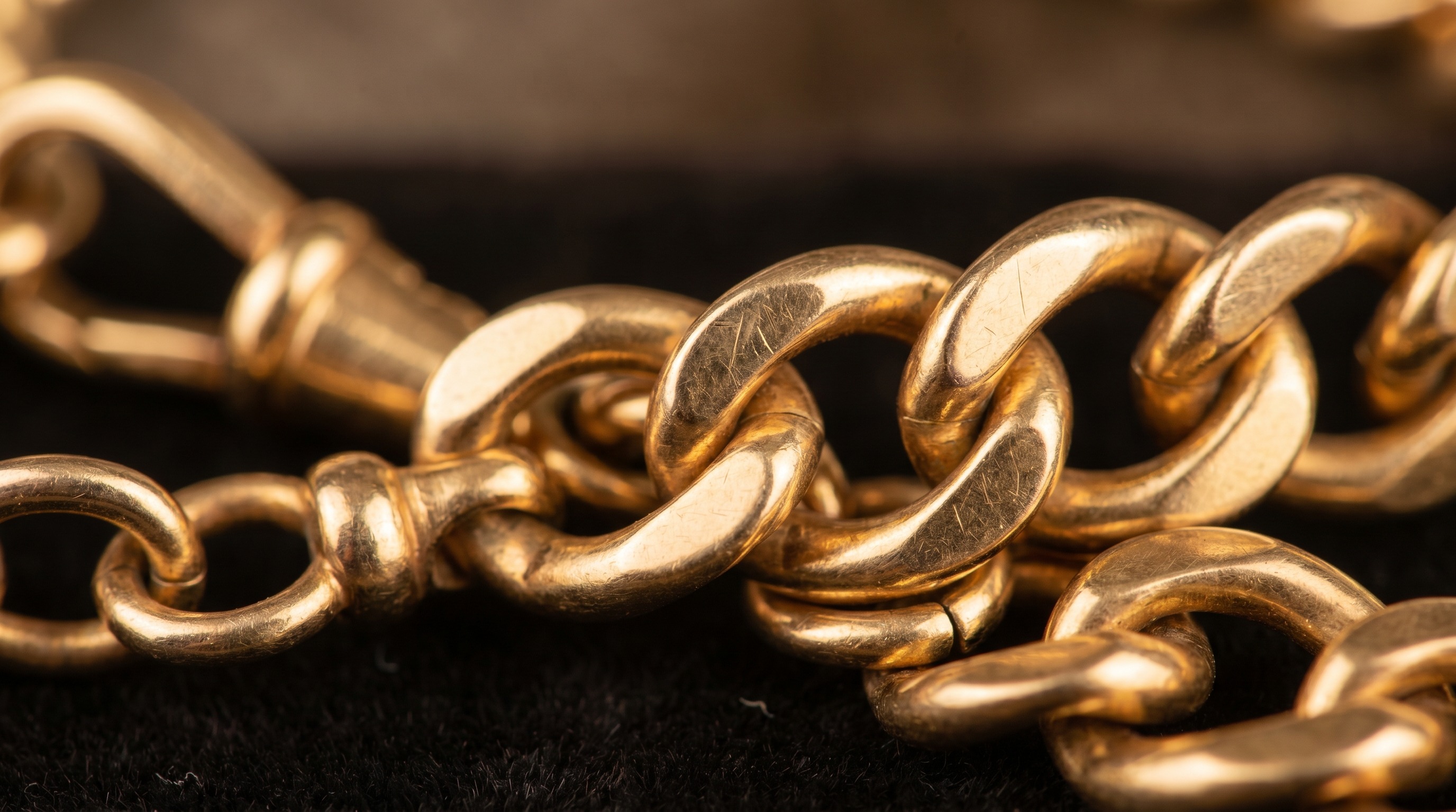 Macro of solid gold curb links and a swivel clasp showing colour and wear