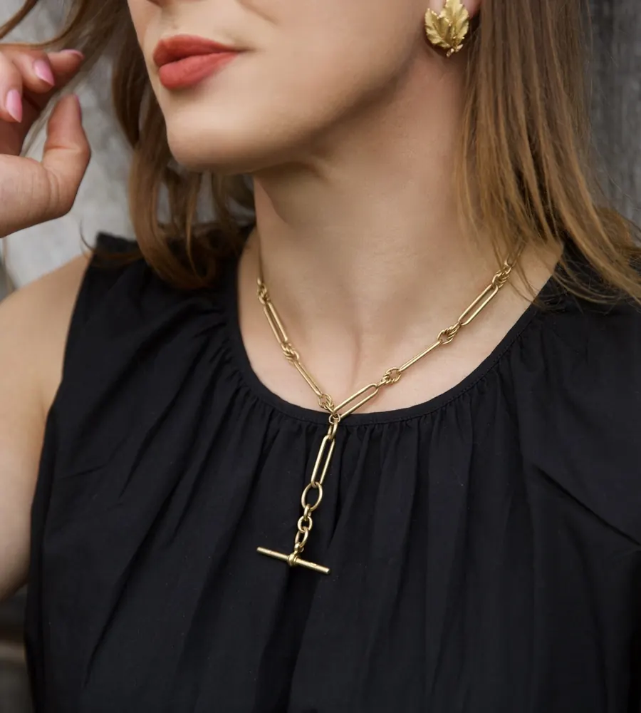 An 18KT gold trombone link Albert chain worn as a necklace with the T-bar at the front