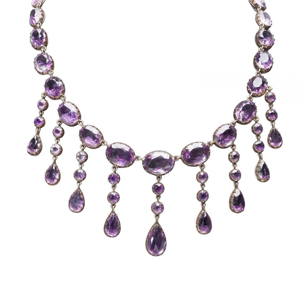 A Victorian amethyst fringe necklace in 9KT gold, about 1880: oval amethysts in collet settings with pear-shaped amethyst drops