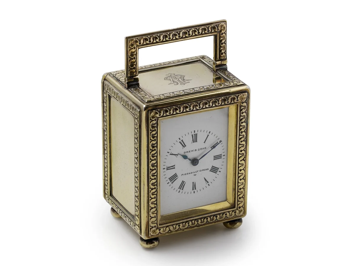 Edwardian silver-gilt carriage clock by Drew and Sons, London 1913, seen from a three-quarter angle with its engraved border and swing handle
