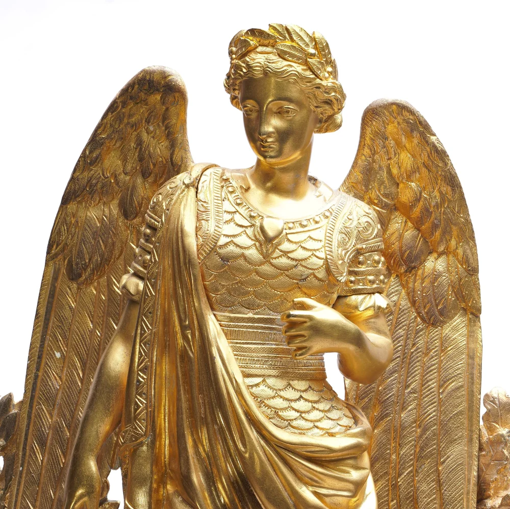 Close-up of the cast and chased gilt bronze winged figure on a French mantel clock, showing the detail of feathers, hair and drapery