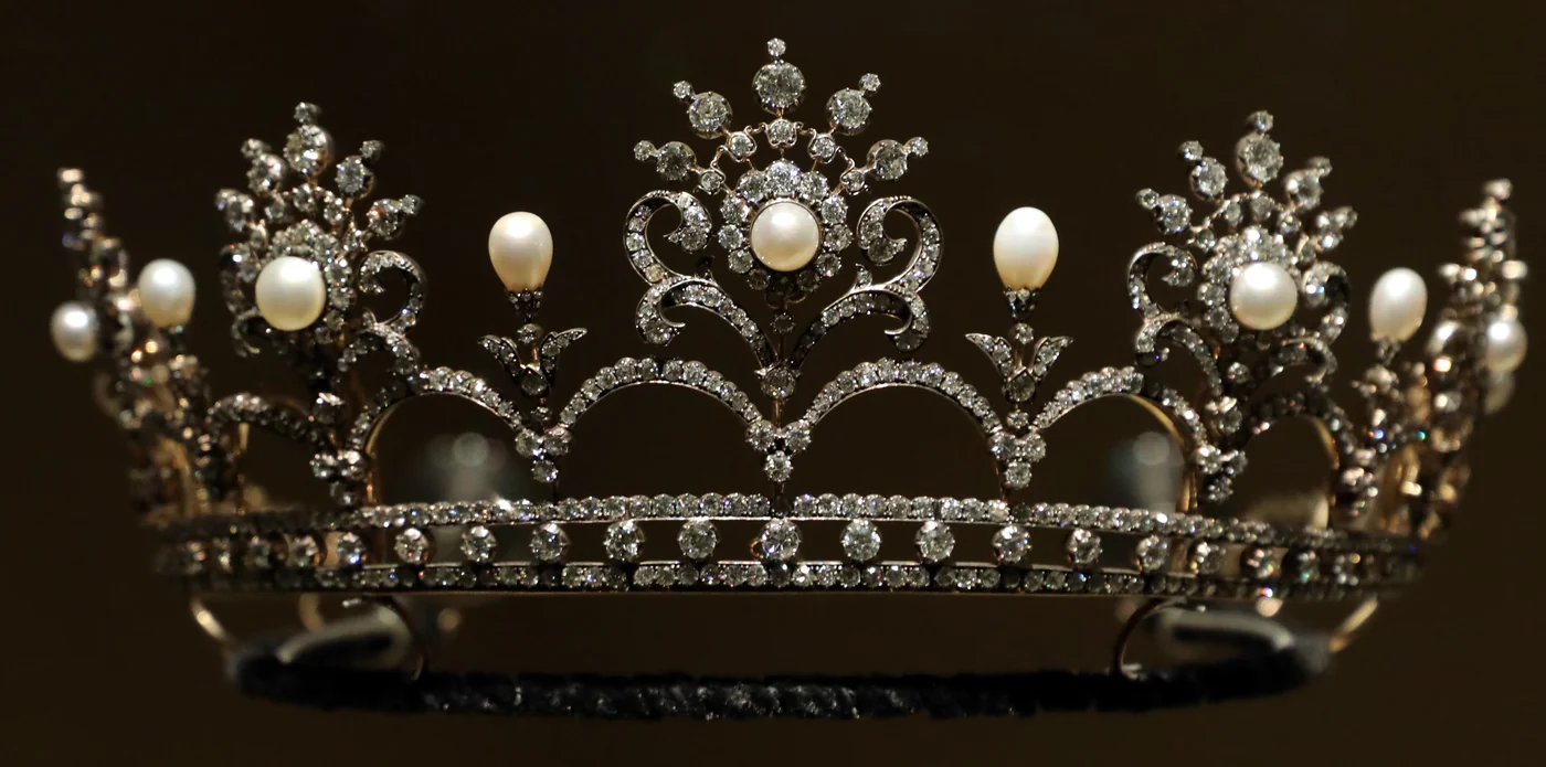 A British diamond and natural pearl tiara of about 1890 on its display stand: scrolling diamond panels topped by pearls on fine spikes, a type that can also be worn as a necklace