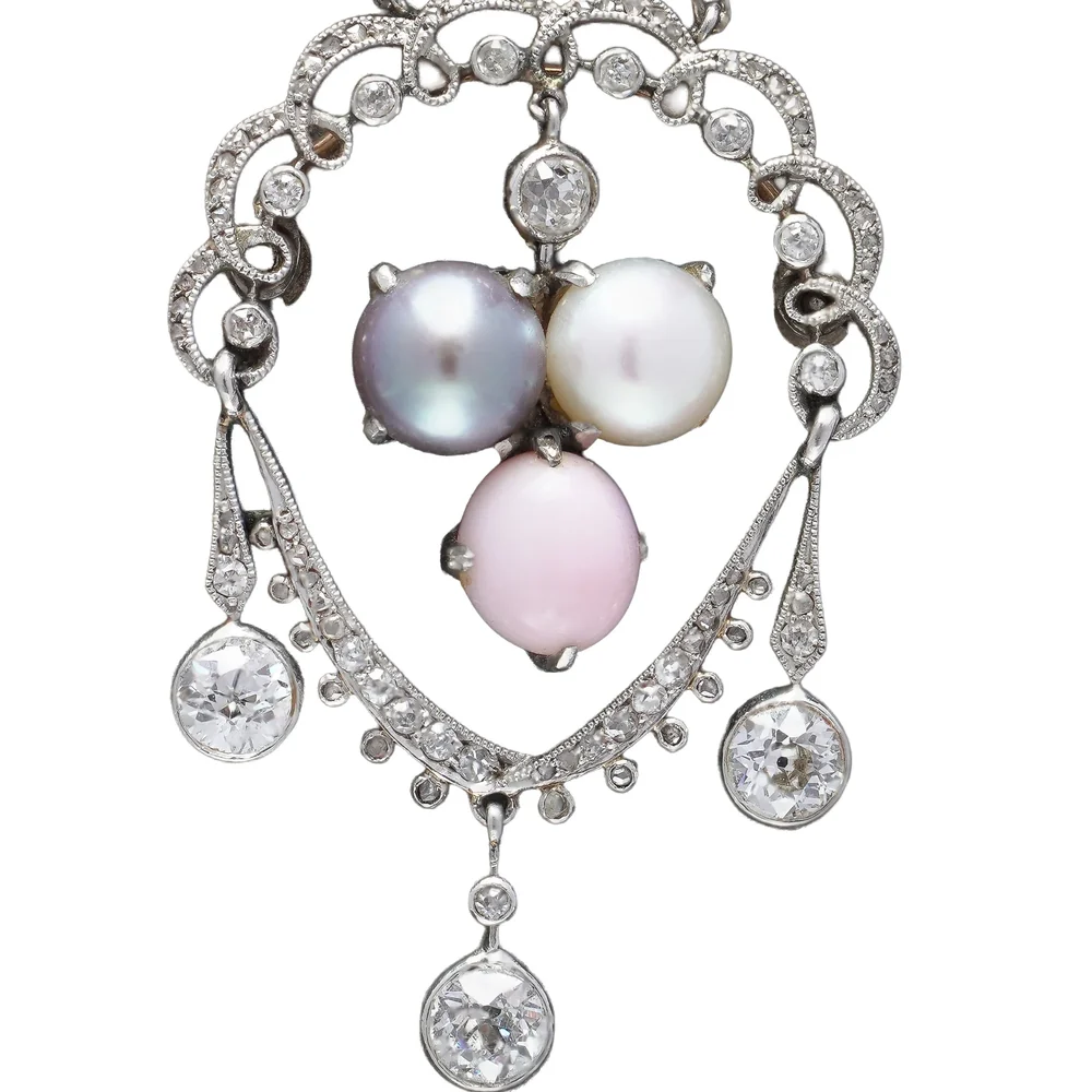Close view of a Belle Epoque platinum pendant: a fine garland of old cut diamonds in millegrained platinum settings around three pearls, with diamond drops