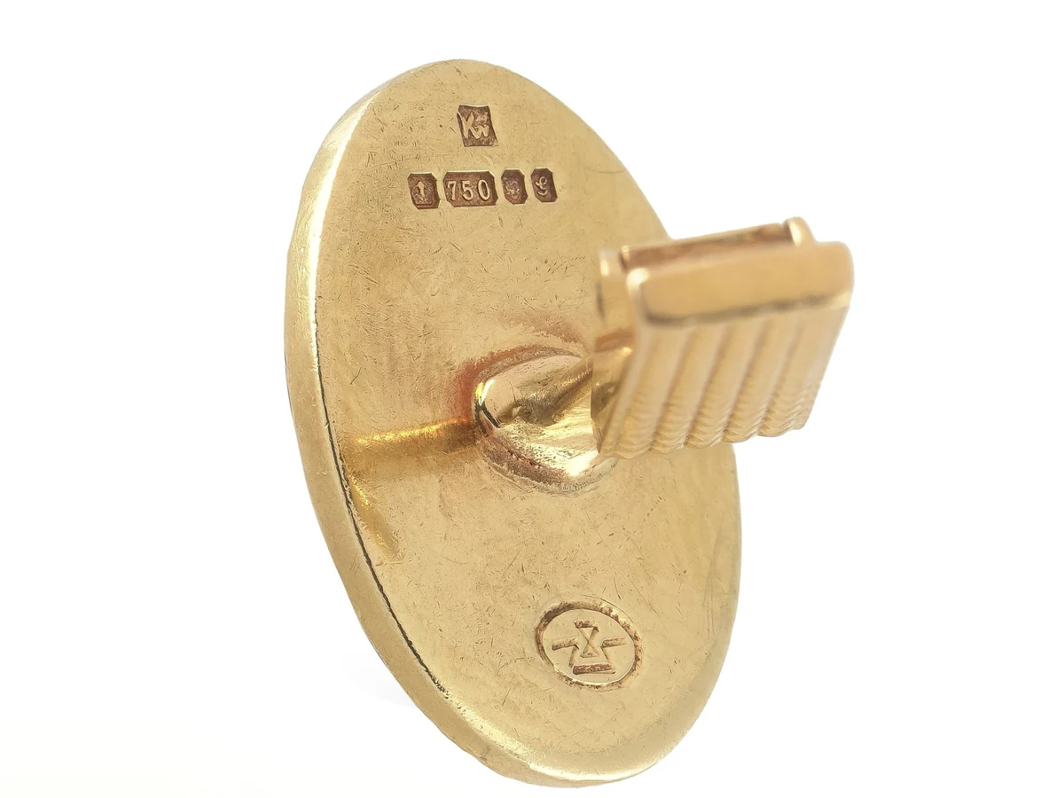 The back of an 18ct gold cufflink with British hallmarks including 750, the mark for 18ct gold