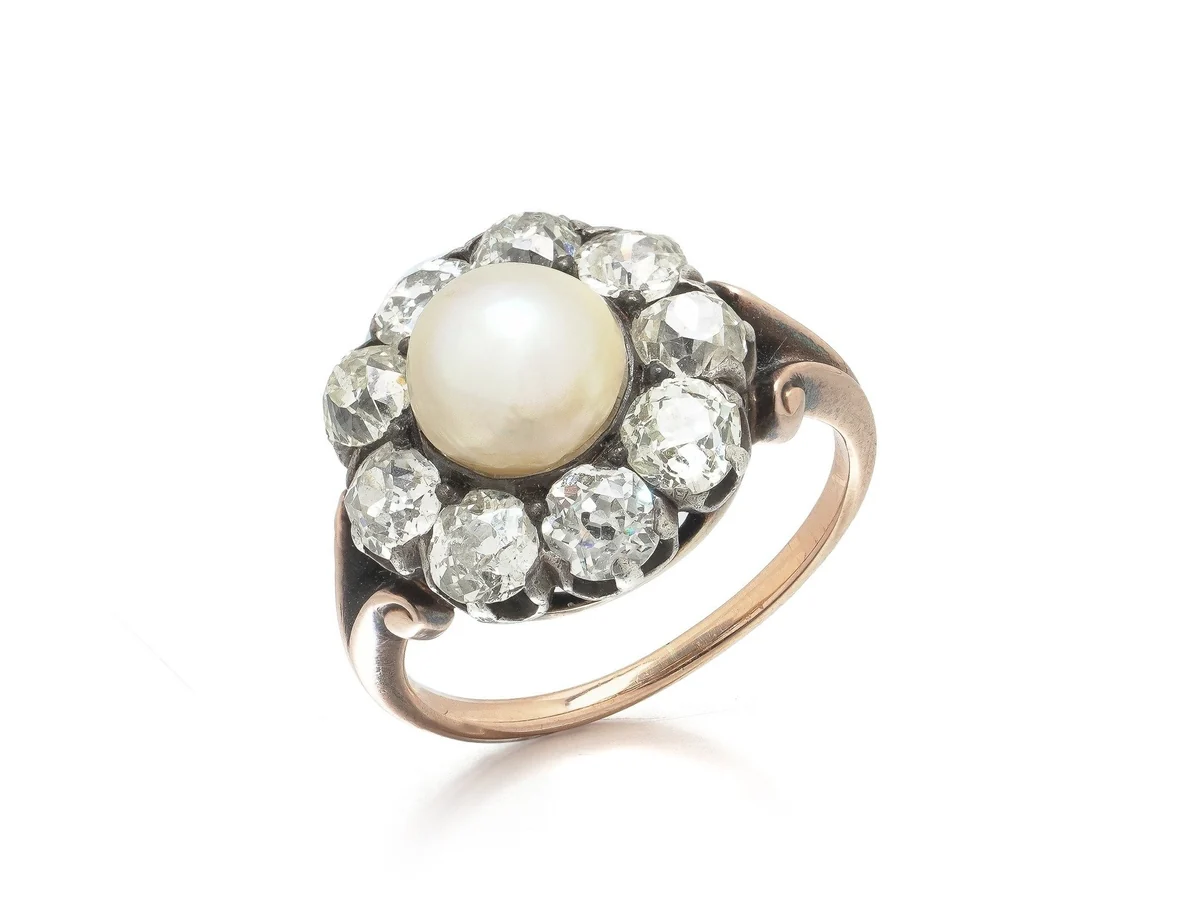 A Victorian cluster ring in 18KT gold: a natural pearl surrounded by old European cut diamonds