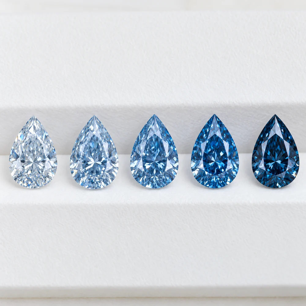 Illustration of five pear-shaped blue diamonds in a row, increasing in colour saturation from pale to deep blue