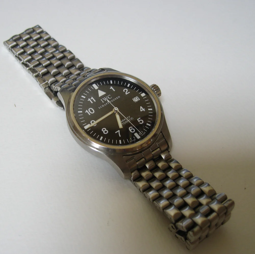 A steel IWC Mark XV pilot's watch with a black dial and white Arabic numerals on a steel bracelet