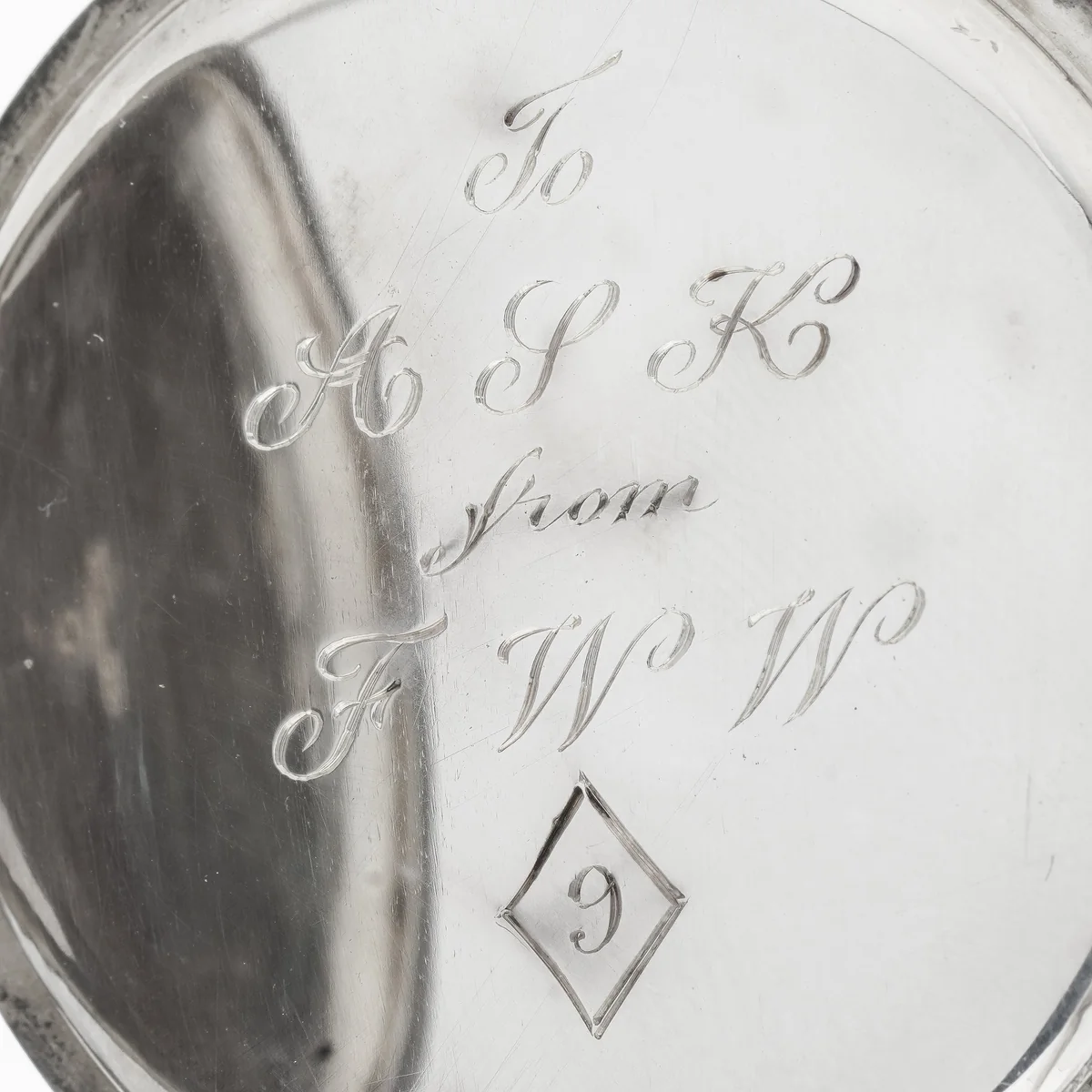The inside cover of a silver Wilsdorf & Davis pocket watch, hand engraved in script: To A S K from F W W
