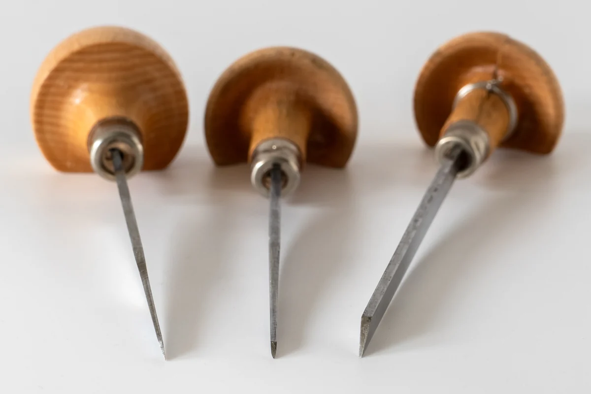 Three hand engraving burins with wooden mushroom handles and steel blades of different profiles