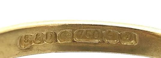 A close-up of the hallmarks inside the shank of an 18ct gold ring from our collection: maker's mark, crown, 750 fineness mark, assay office mark and date letter