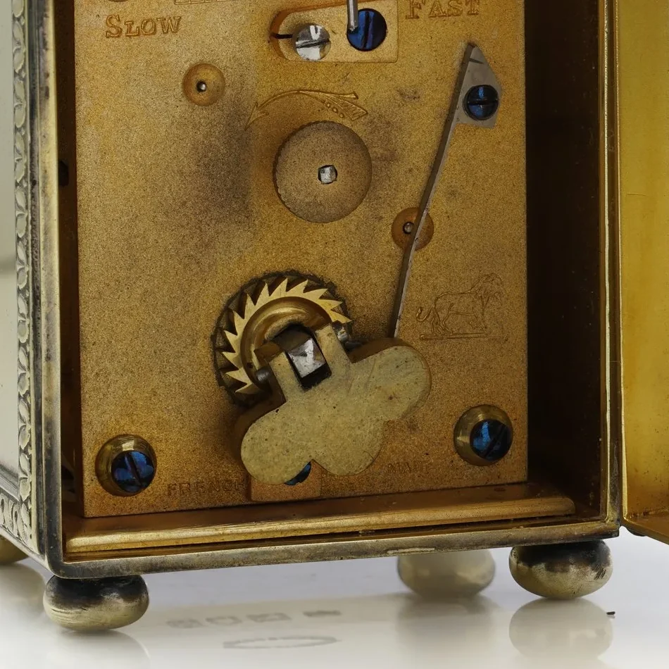 Carriage clock backplate stamped French Made, with a lion trademark and Slow and Fast regulation marks