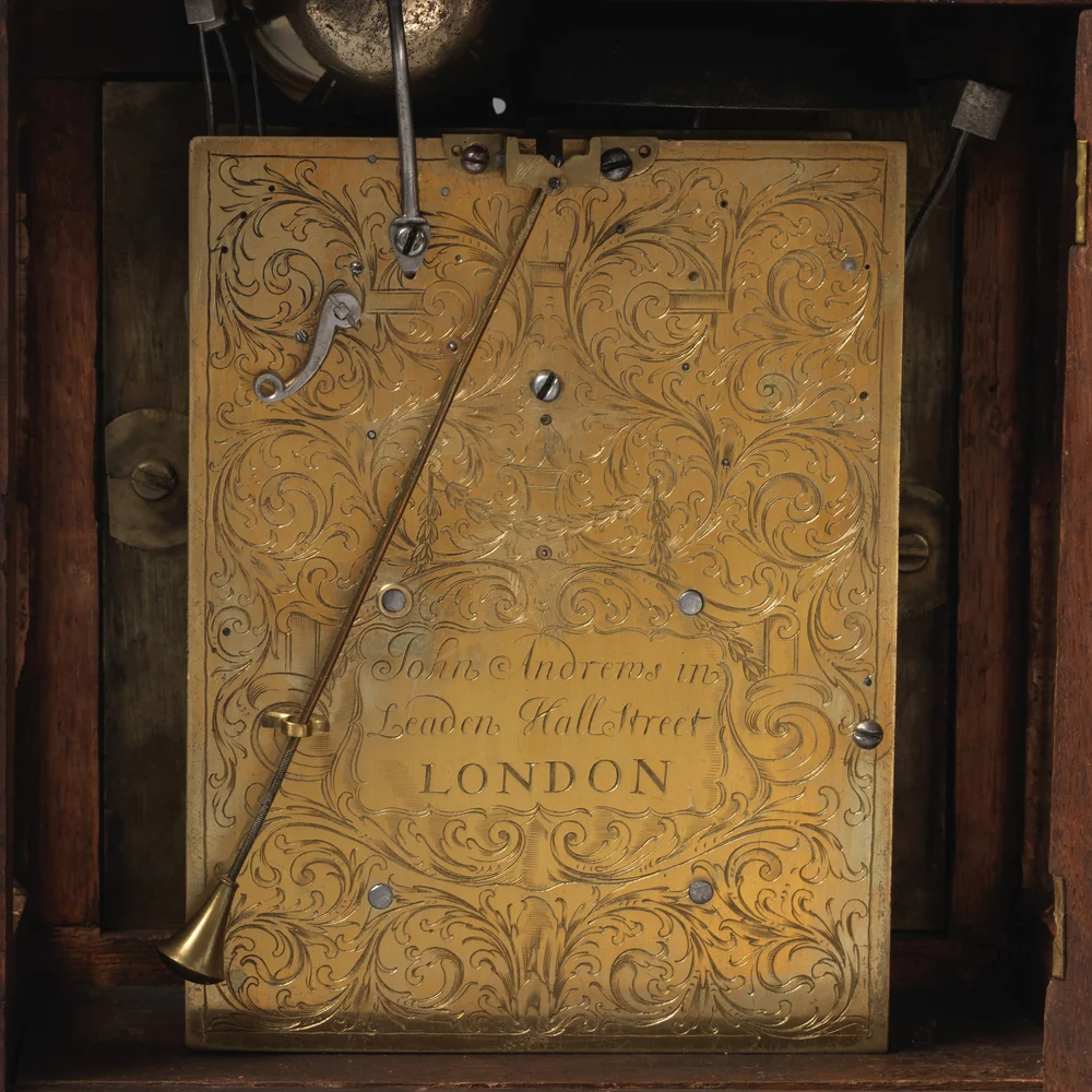 Engraved brass backplate of a bracket clock by John Andrews, London, 1690, with scrolling foliage and the maker's signature