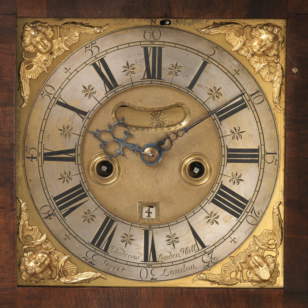 Square brass dial of a London bracket clock of 1690, with a silvered chapter ring, Roman numerals and cast gilt corner spandrels
