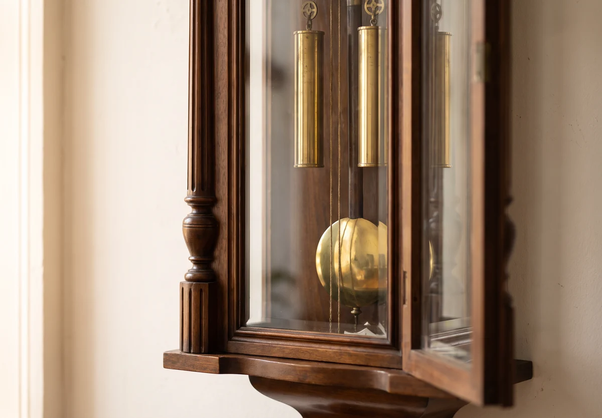 The glazed lower case of a Vienna regulator with its brass pendulum bob and three weights