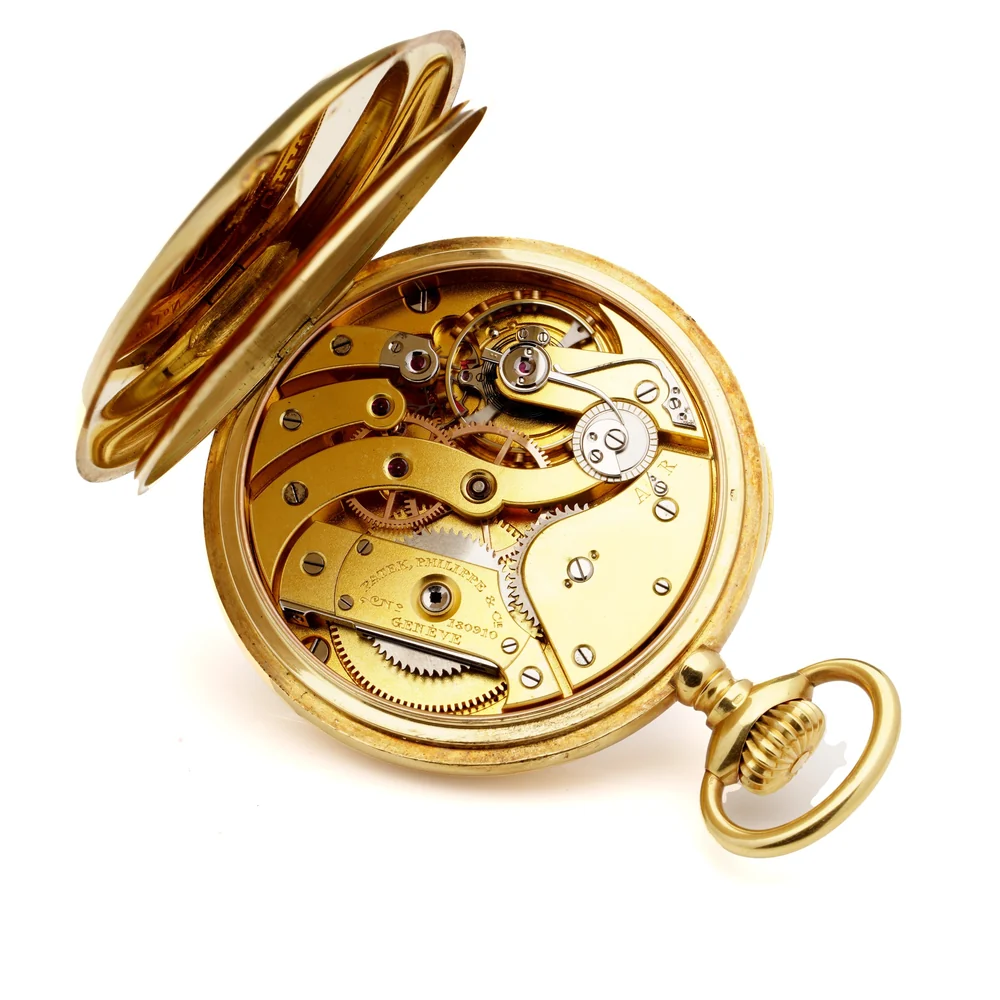Gilt Patek Philippe pocket watch movement with separate bridges, seen through the opened case back