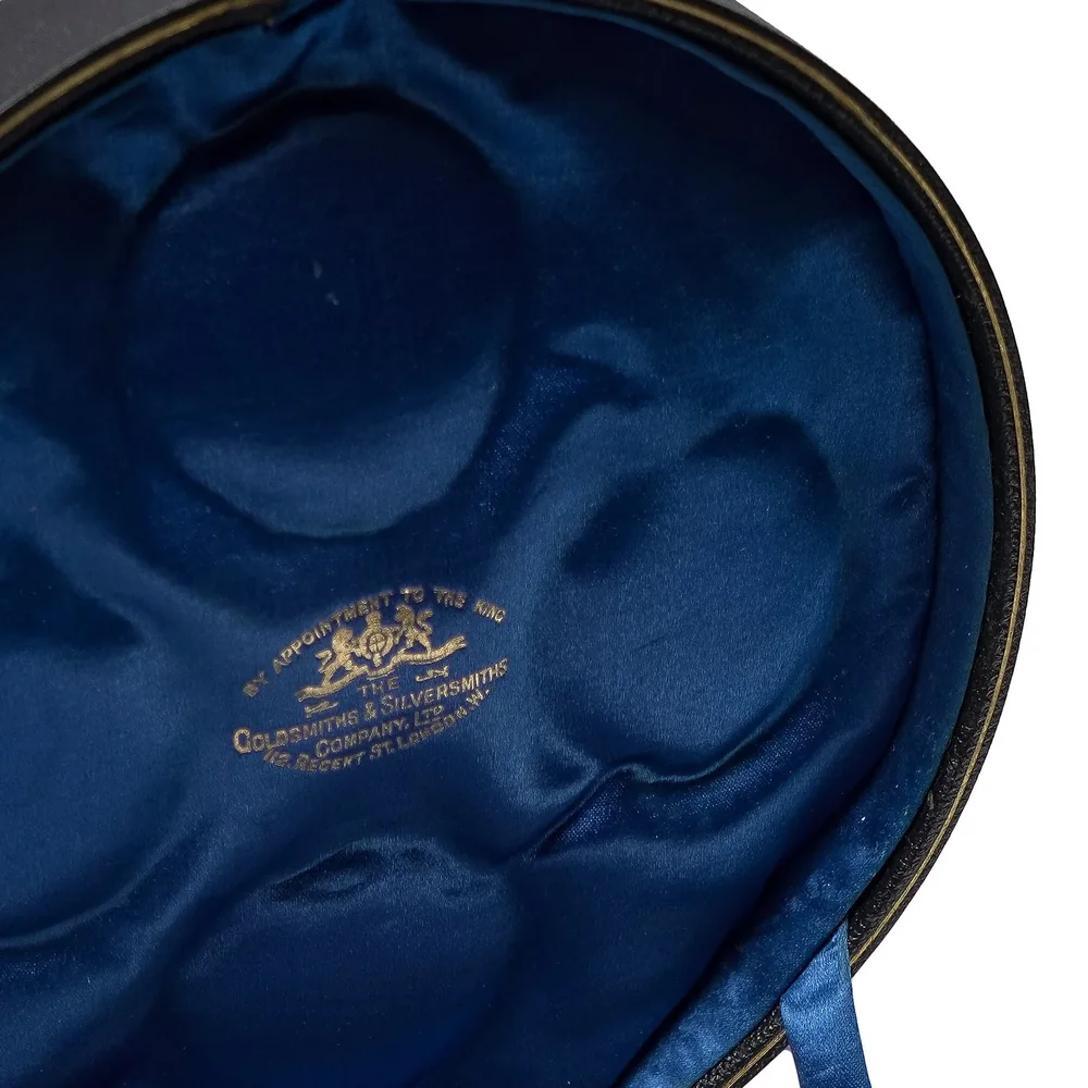 Blue satin lid of a fitted Goldsmiths & Silversmiths Company Ltd case printed in gilt with the royal arms, By Appointment to the King, 112 Regent St, London