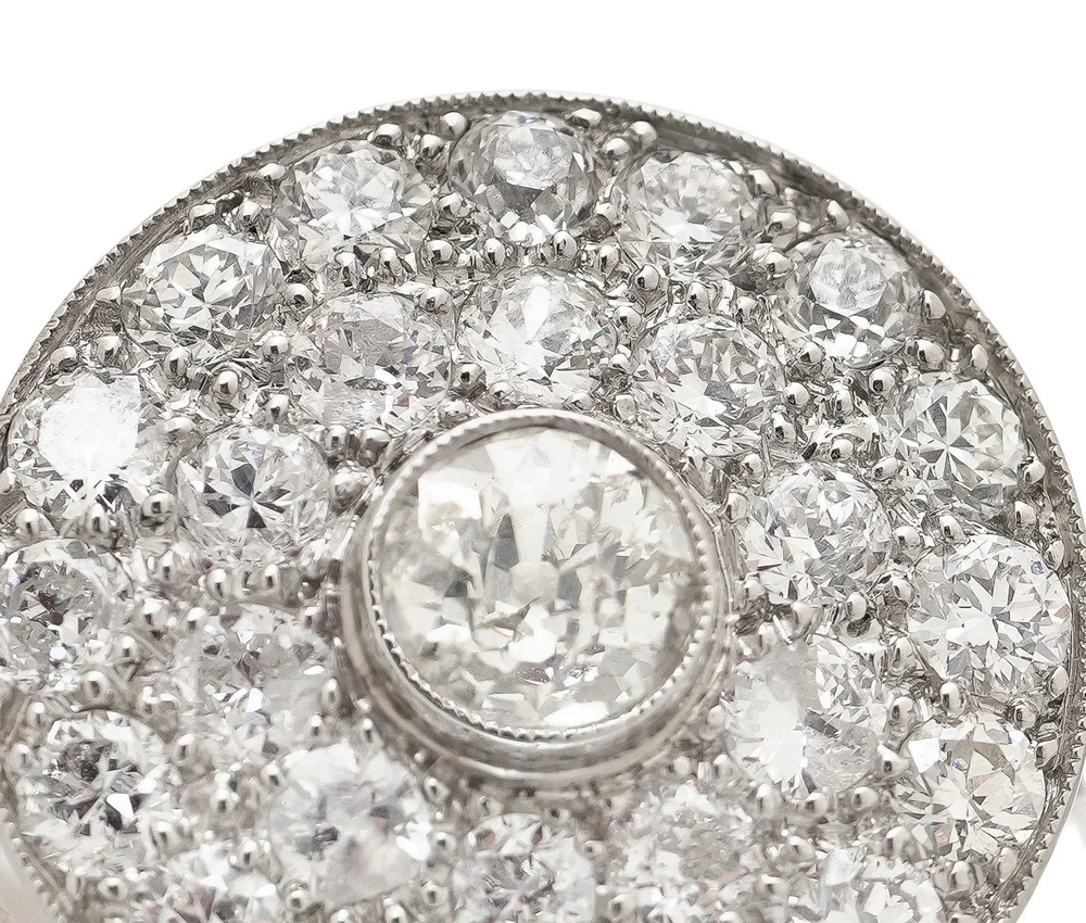 An Art Deco platinum target cluster ring with an old European cut diamond at the centre, showing its small table and open culet