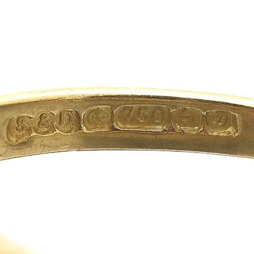 Hallmark inside the shank of the ruby half hoop ring: sponsor S&D, a crown, the number 750, the Birmingham anchor and a date letter
