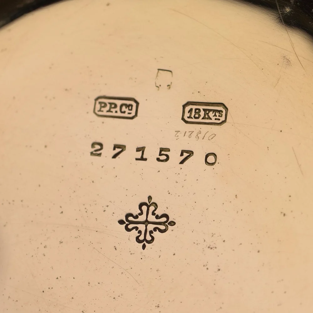 Inside a gold pocket watch case back: maker's mark PP.Co, 18Kts gold standard, case number and a smaller number scratched by hand