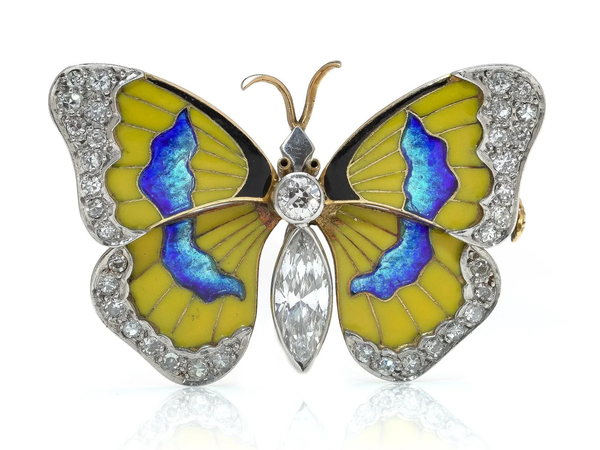 A butterfly brooch with yellow enamel wings, iridescent blue enamel panels, old cut diamond borders and a marquise diamond body