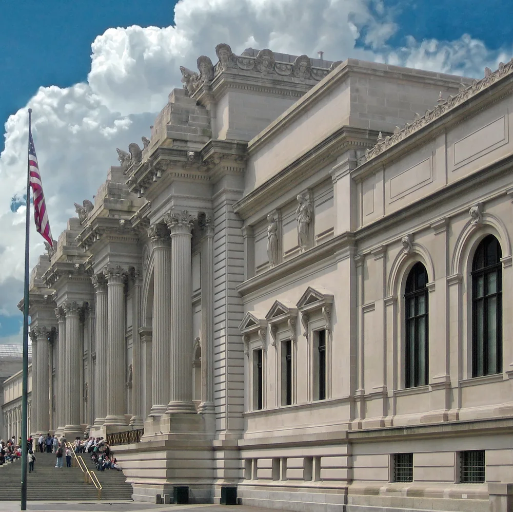 The columned Fifth Avenue facade of the Metropolitan Museum of Art in New York, with visitors on the front steps