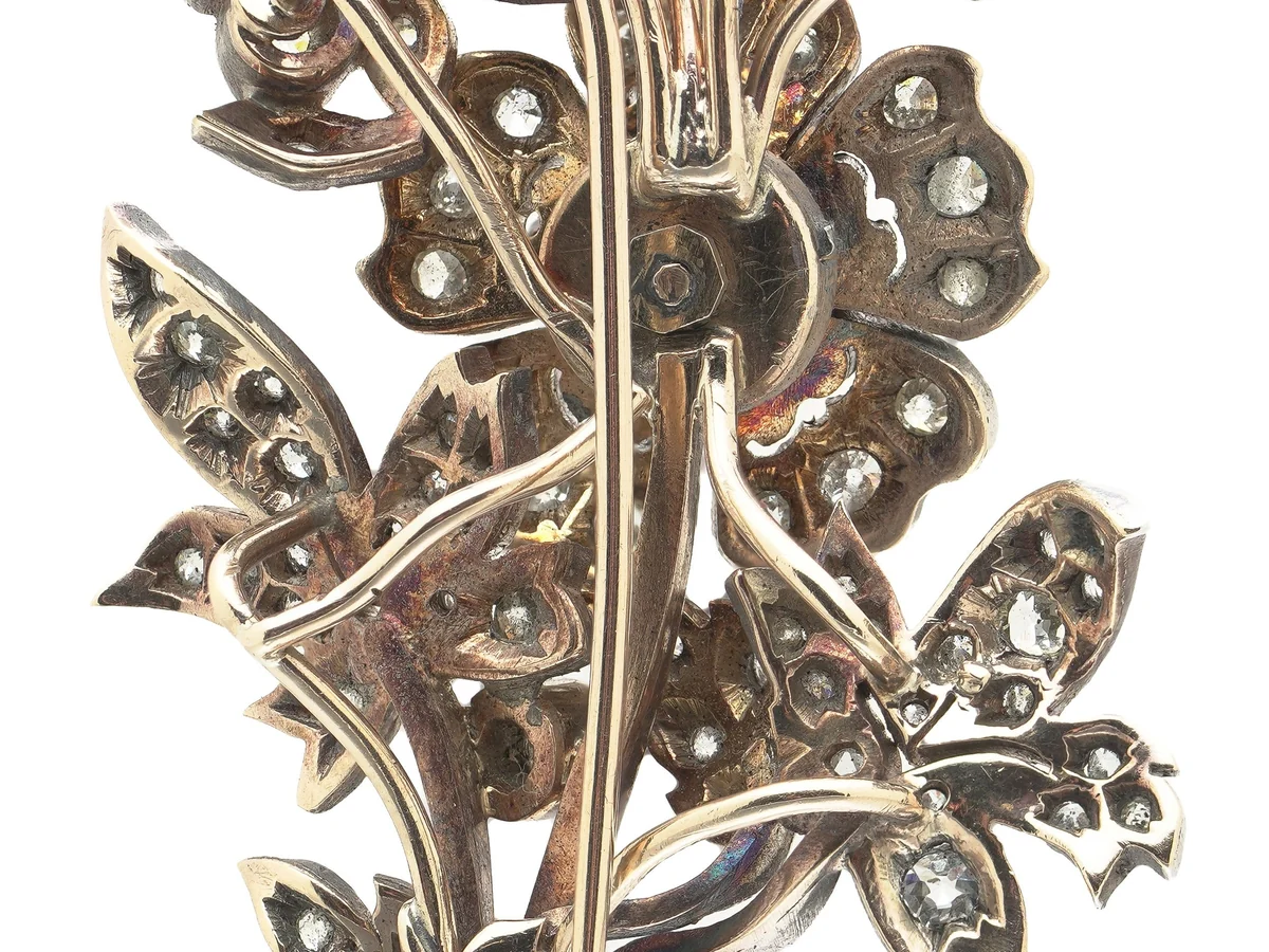 The reverse of a Victorian diamond flower spray brooch, showing the gold back behind silver-set diamonds and the pin fitting