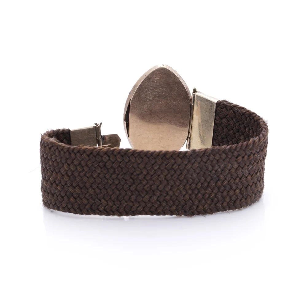 The back of a Georgian mourning bracelet: a wide band of tightly plaited brown hair between gold end caps and a plain gold back plate