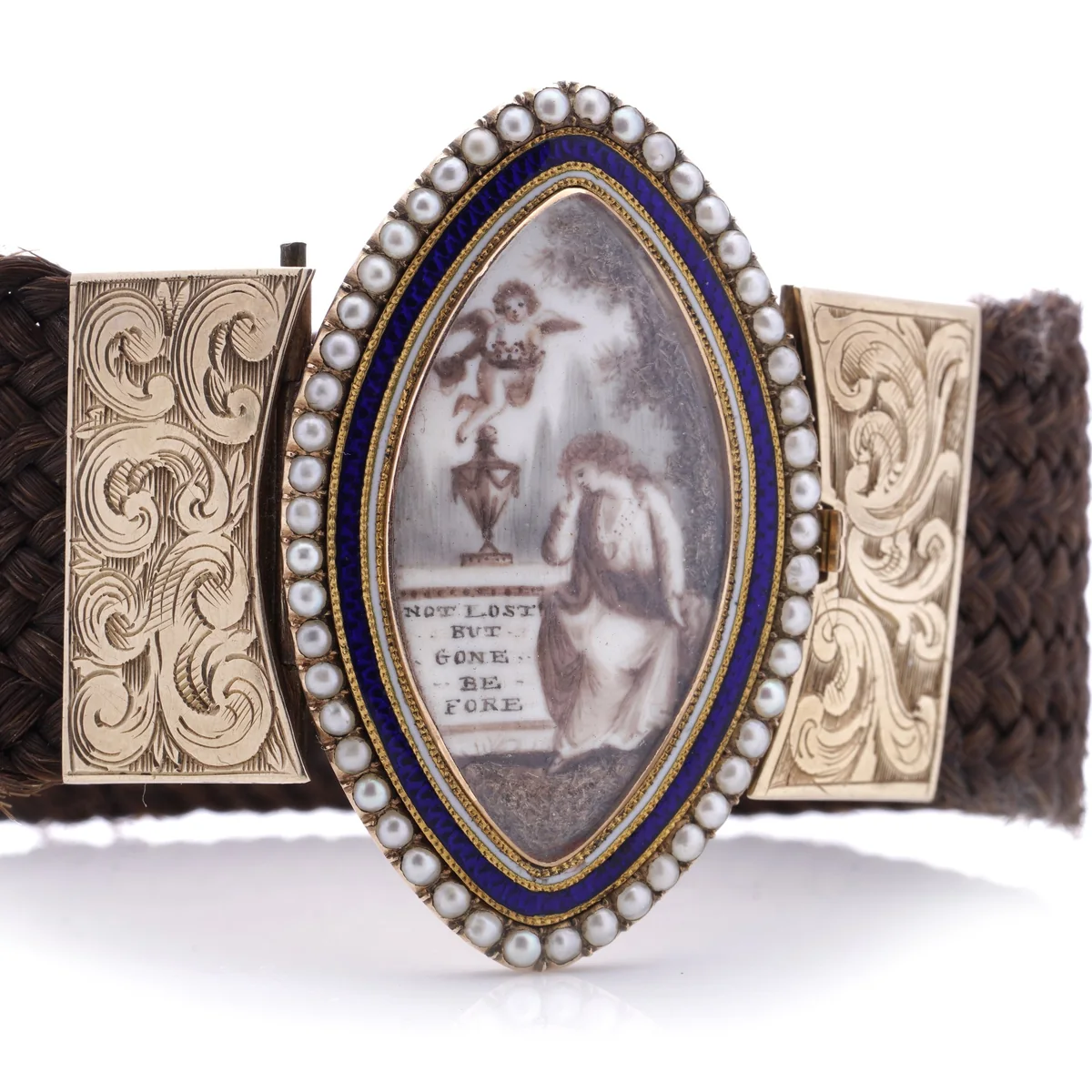 A late Georgian mourning bracelet: a marquise panel painted in sepia with a mourning woman beside an urn on a plinth inscribed Not lost but gone before, a cherub above, framed in blue enamel and seed pearls, on a band of plaited brown hair with engraved gold clasps
