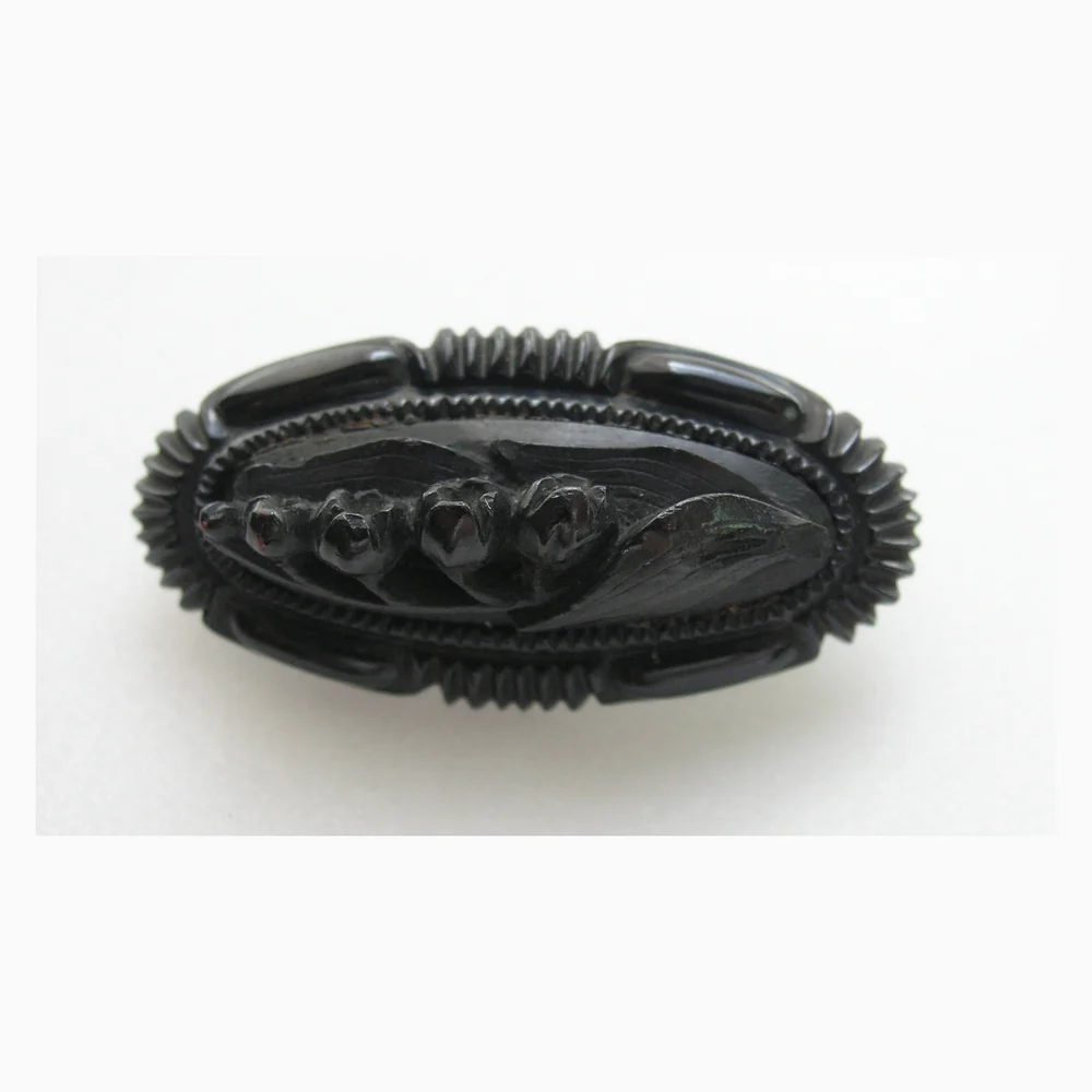 A late 19th century carved jet brooch with a raised spray of lily of the valley inside a fluted border