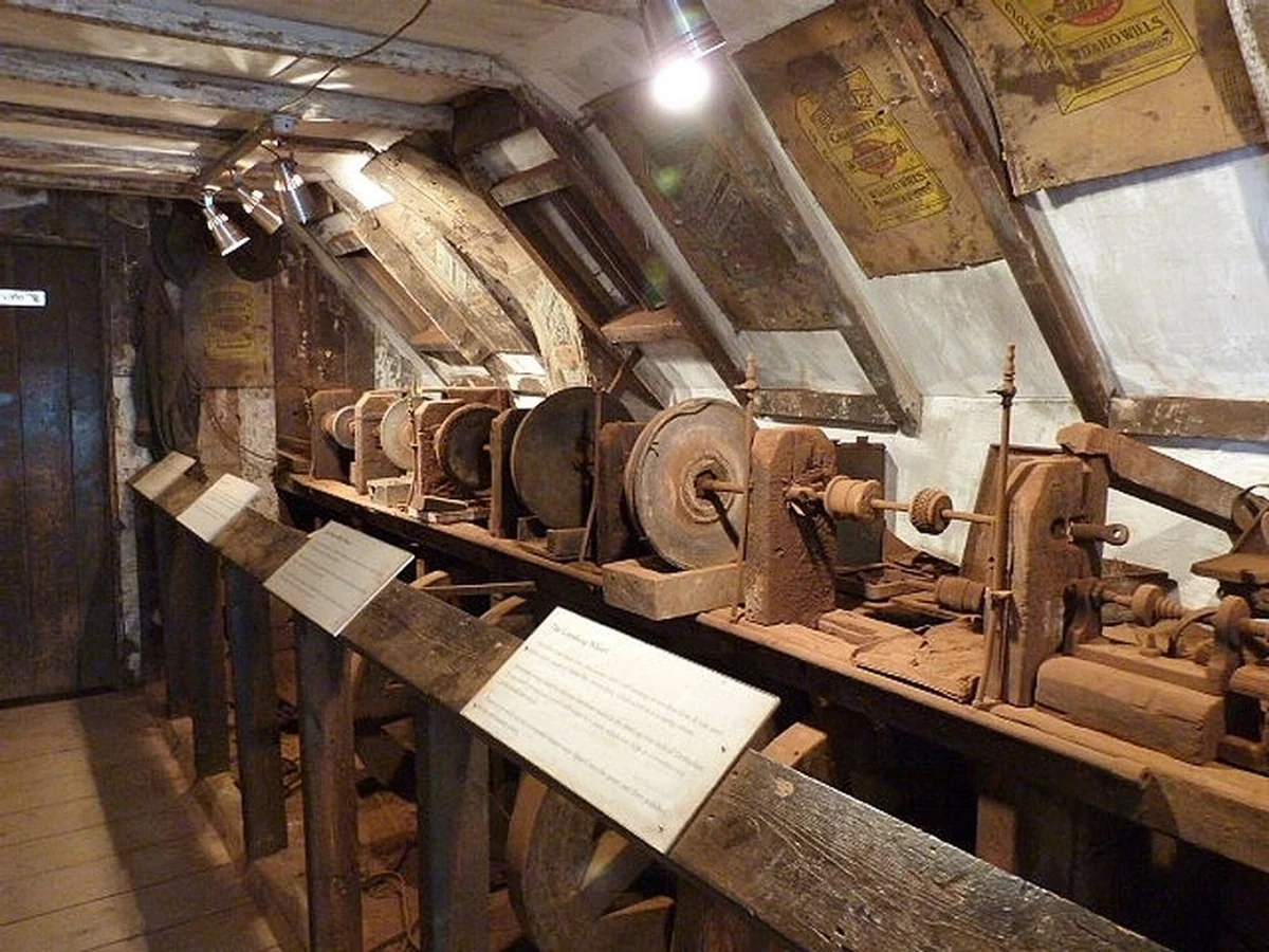 The preserved attic workshop of a Whitby jet jeweller, with belt-driven lathes and grinding wheels along a wooden bench under the eaves