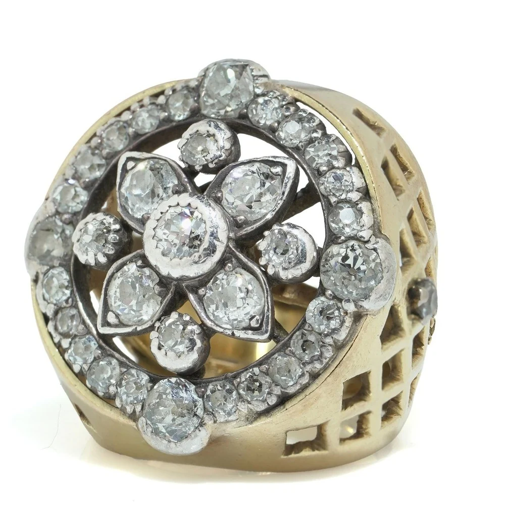 Early 20th-century cluster ring set with old European cut diamonds in a flower pattern, with pierced lattice shoulders