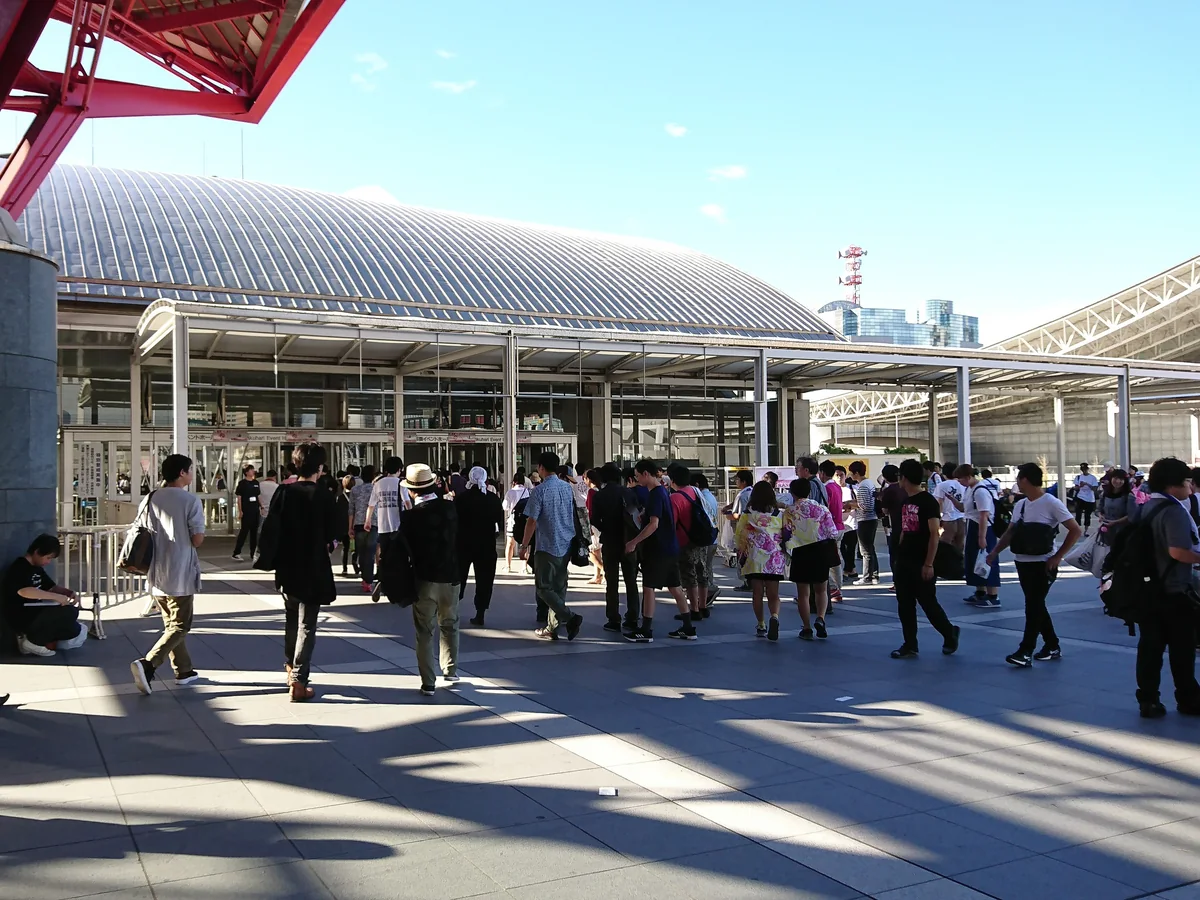 The entrance to Makuhari Event Hall at Makuhari Messe, Chiba, Japan, with its curved silver roof and visitors walking in