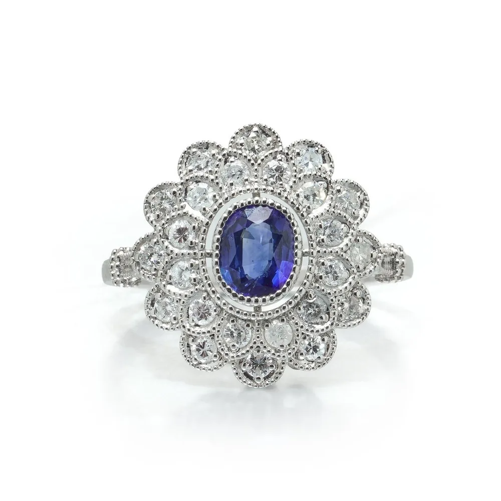 Art Deco style platinum ring with an oval Ceylon sapphire inside two rows of diamonds set in scalloped milgrain petals, seen front on