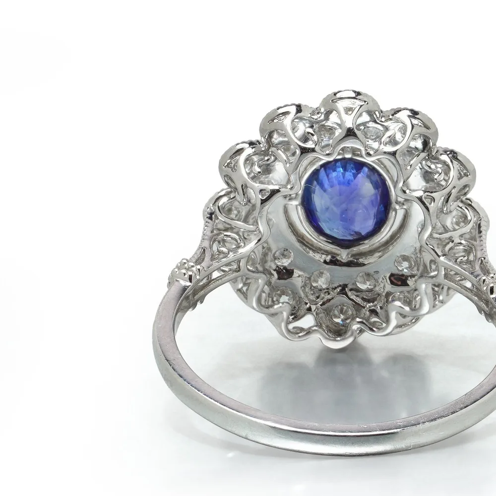 Underside of a sapphire and diamond cluster ring showing the open pierced gallery behind the stones and the plain platinum shank